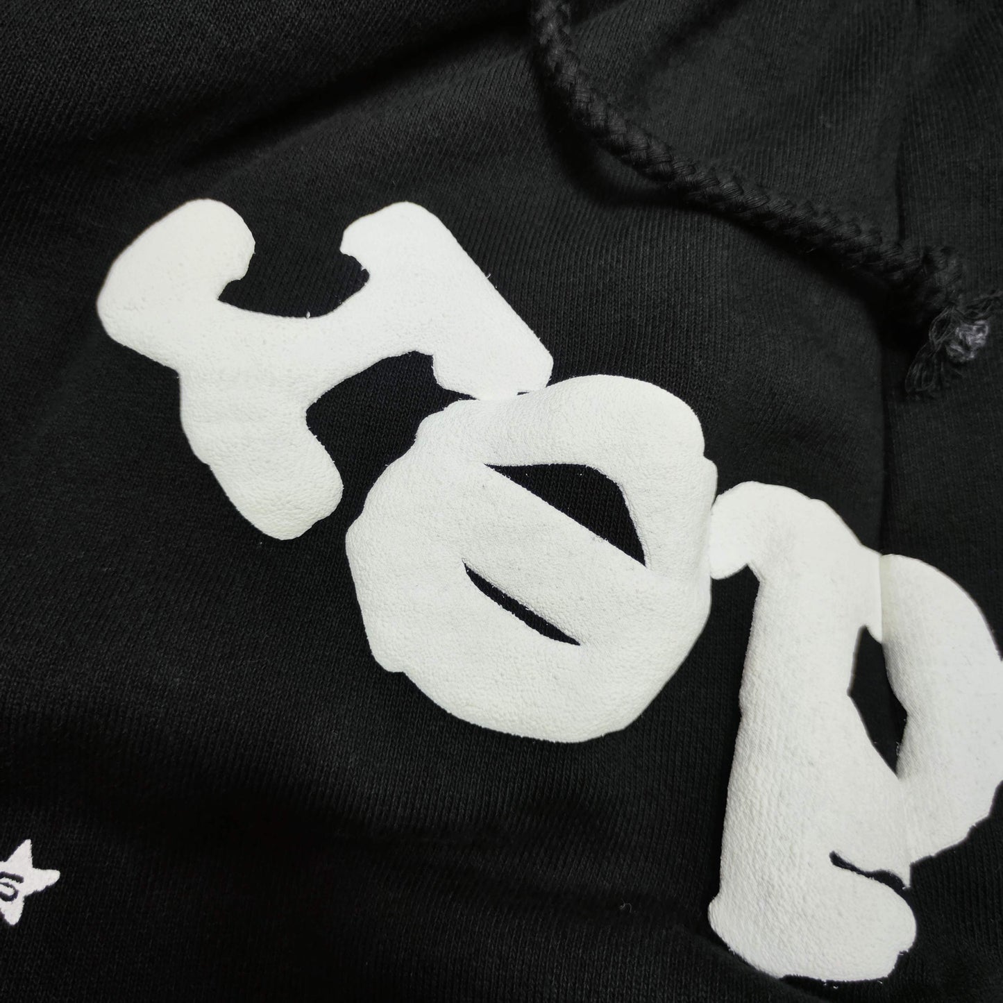 Raised white puff-print texture on SP5DER OG Web black sweatpants