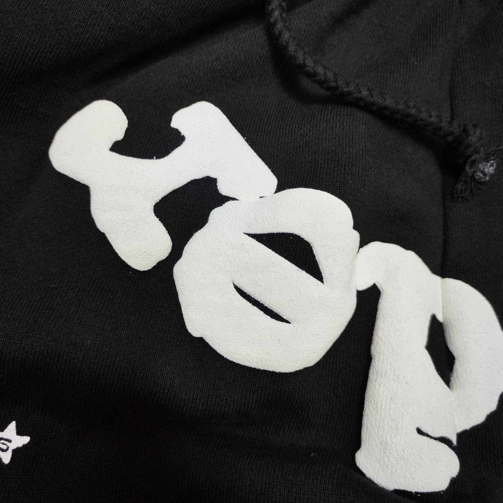 Raised white puff-print texture on SP5DER OG Web black sweatpants