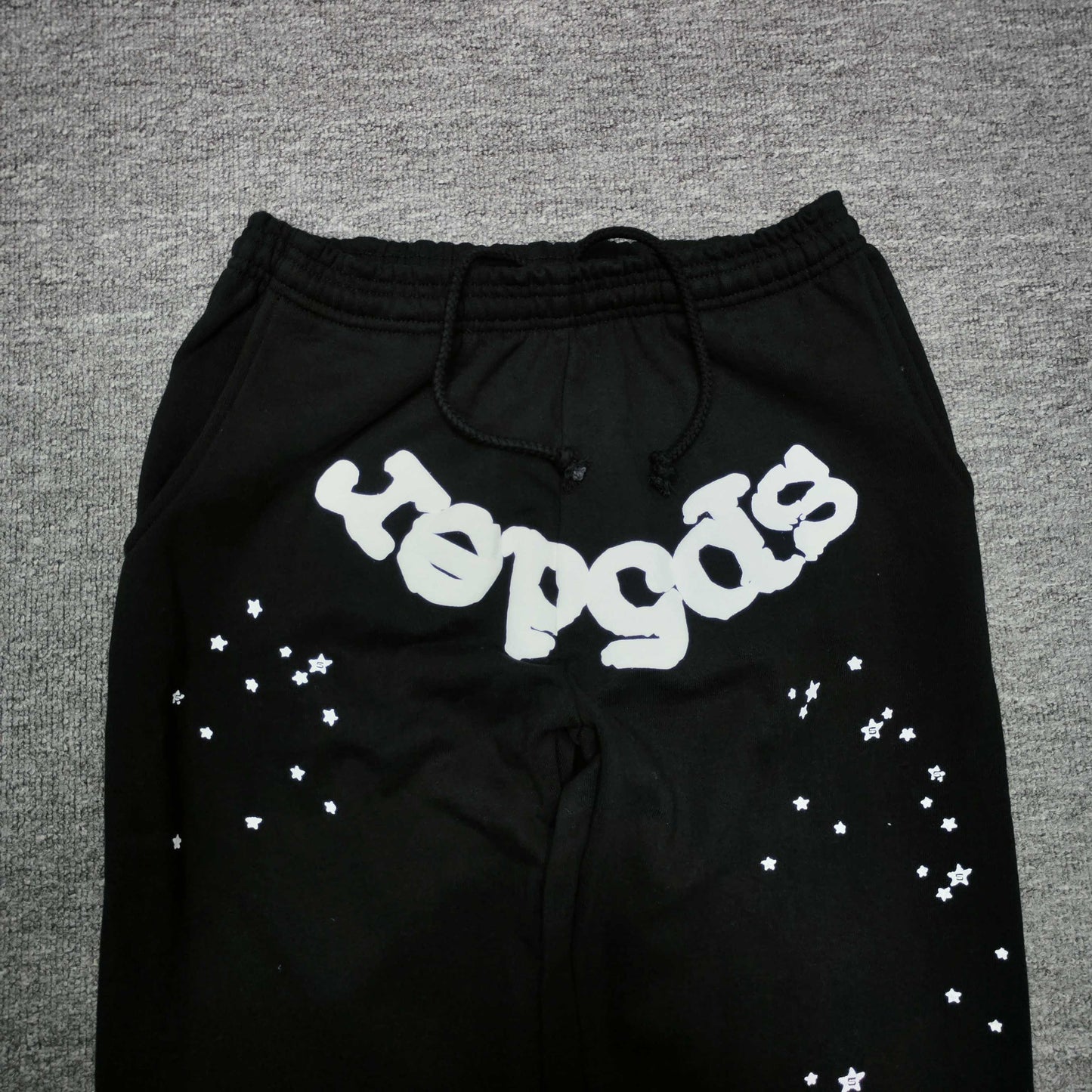 White SP5DER logo and scattered star graphics on black OG Web sweatpants