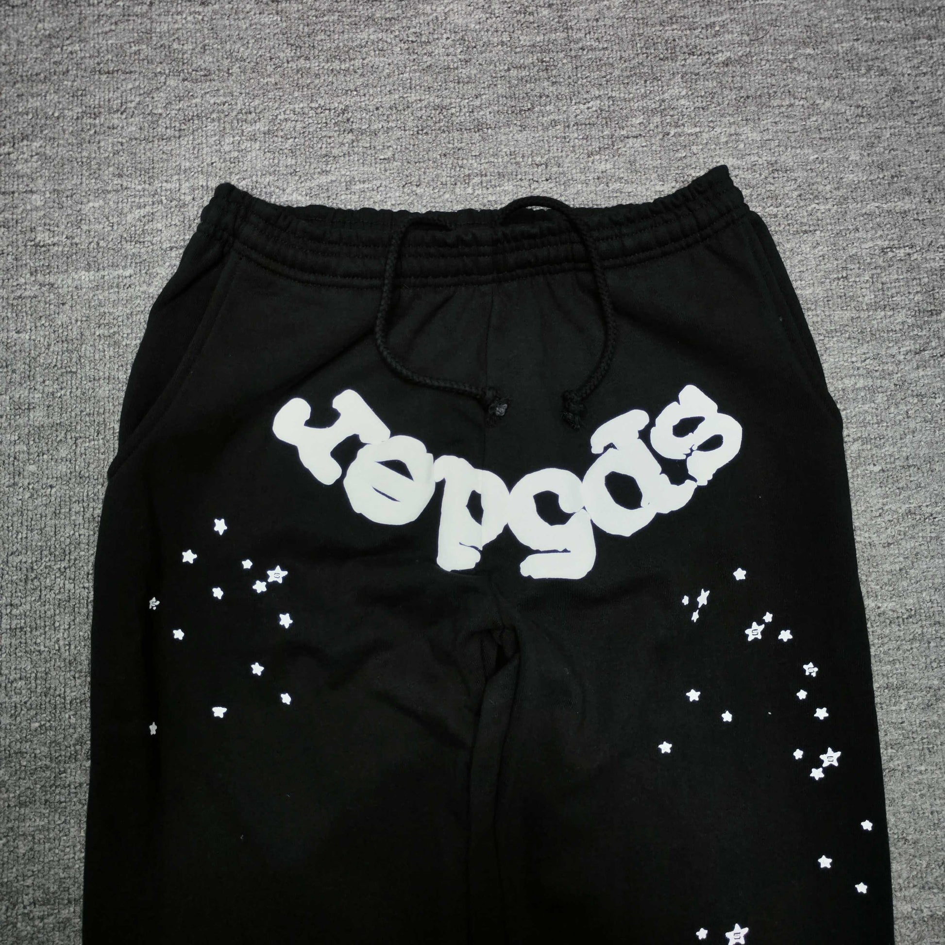 White SP5DER logo and scattered star graphics on black OG Web sweatpants