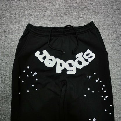White SP5DER logo and scattered star graphics on black OG Web sweatpants
