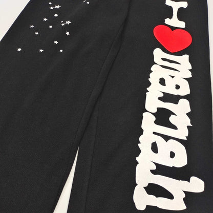 Scattered white star graphics on SP5DER Souvenir black sweatpants