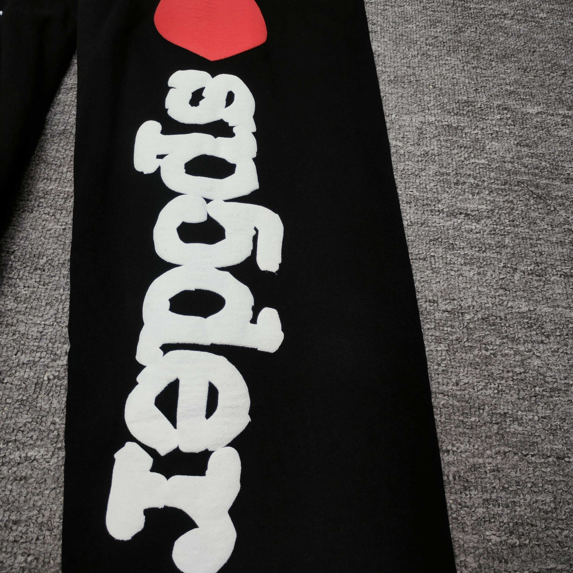 White I Heart SP5DER leg graphic with red heart on black Souvenir sweatpants
Raised white puff-print texture on SP5DER Souvenir black sweatpants