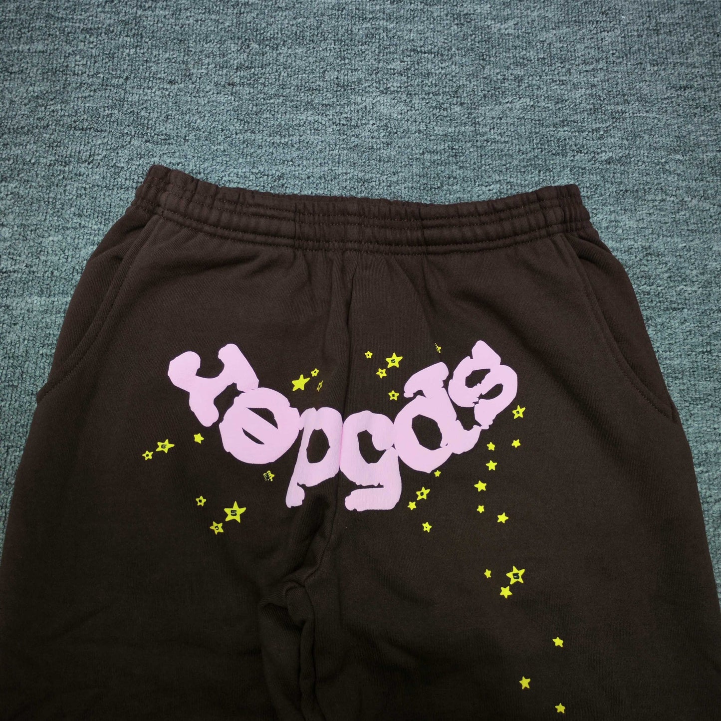 Pink inverted SP5DER logo and yellow star graphics on Classic brown sweatpants