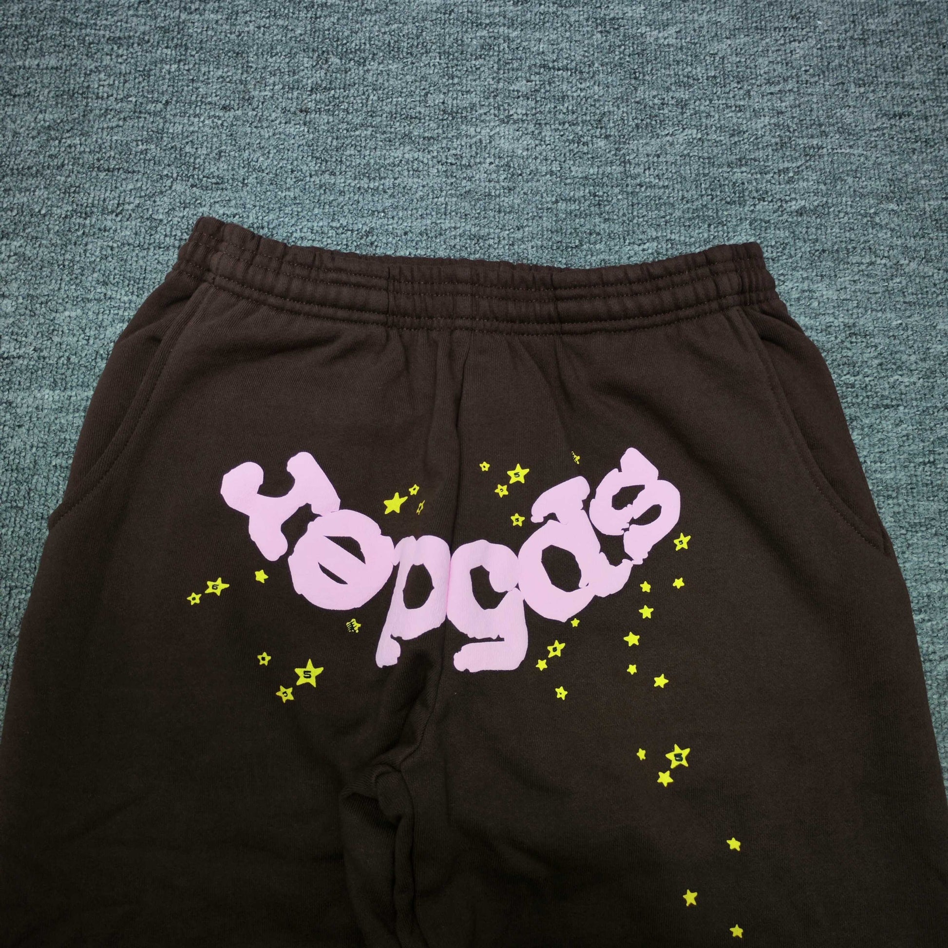 Pink inverted SP5DER logo and yellow star graphics on Classic brown sweatpants