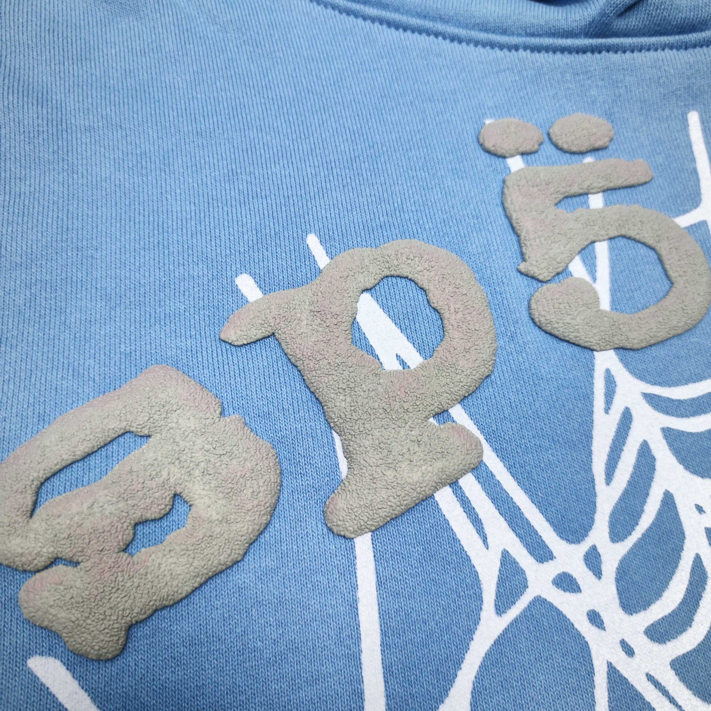 Full front artwork on Sp5der OG Web V2 Hoodie Dusty Blue with grey puff logo and white web
Close-up of raised grey SP5DER puff-print lettering on the Dusty Blue OG Web V2 Hoodie
Side angle showing the three-dimensional grey puff-print texture on Sp5der Dusty Blue Hoodie
Close-up of the white Web V2 spider-web graphic on Sp5der OG Hoodie Dusty Blue