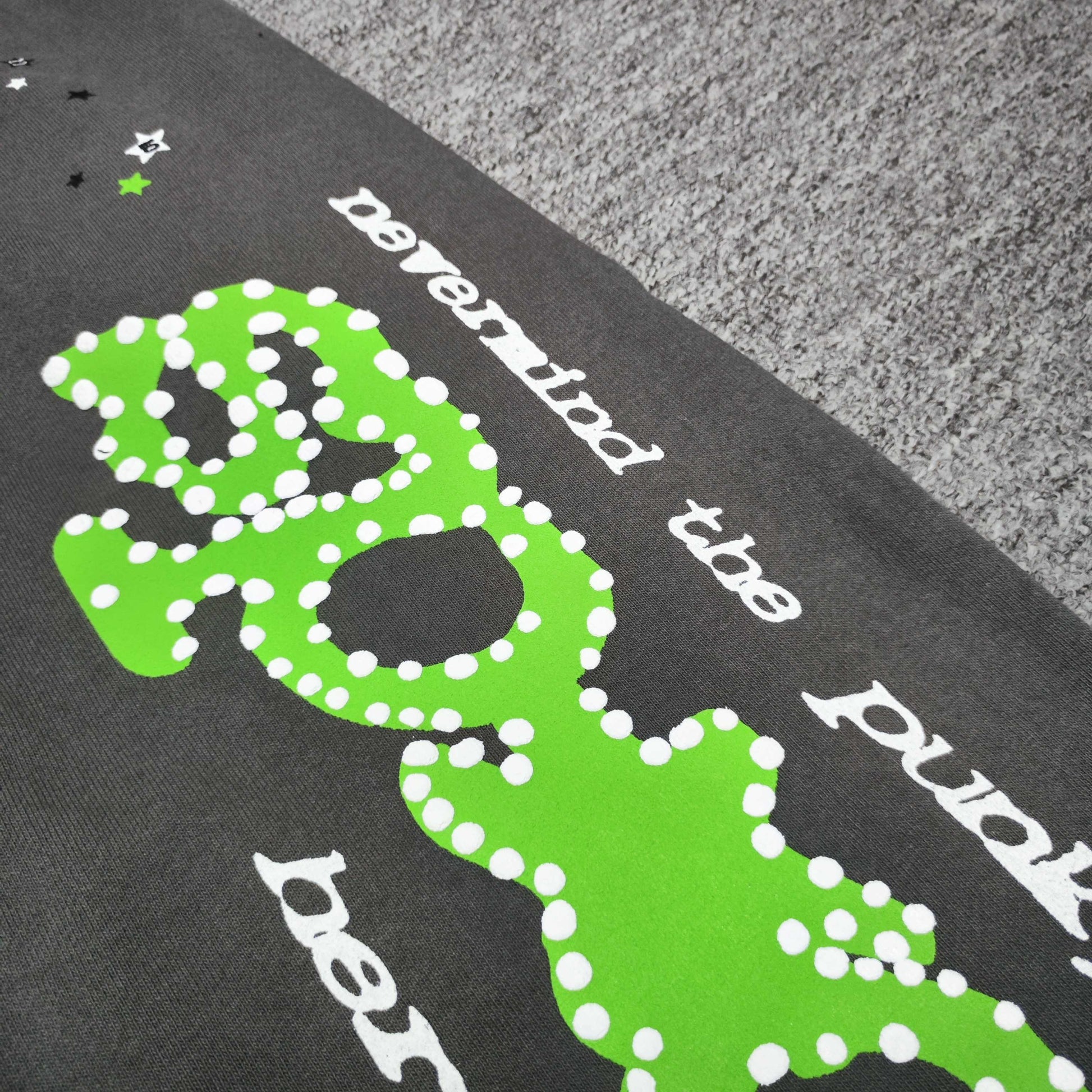 Close-up of green SP5DER puff-print graphic on slate grey Punk V2 sweatpants
White dot detailing around the green SP5DER graphic on Punk V2 sweatpants