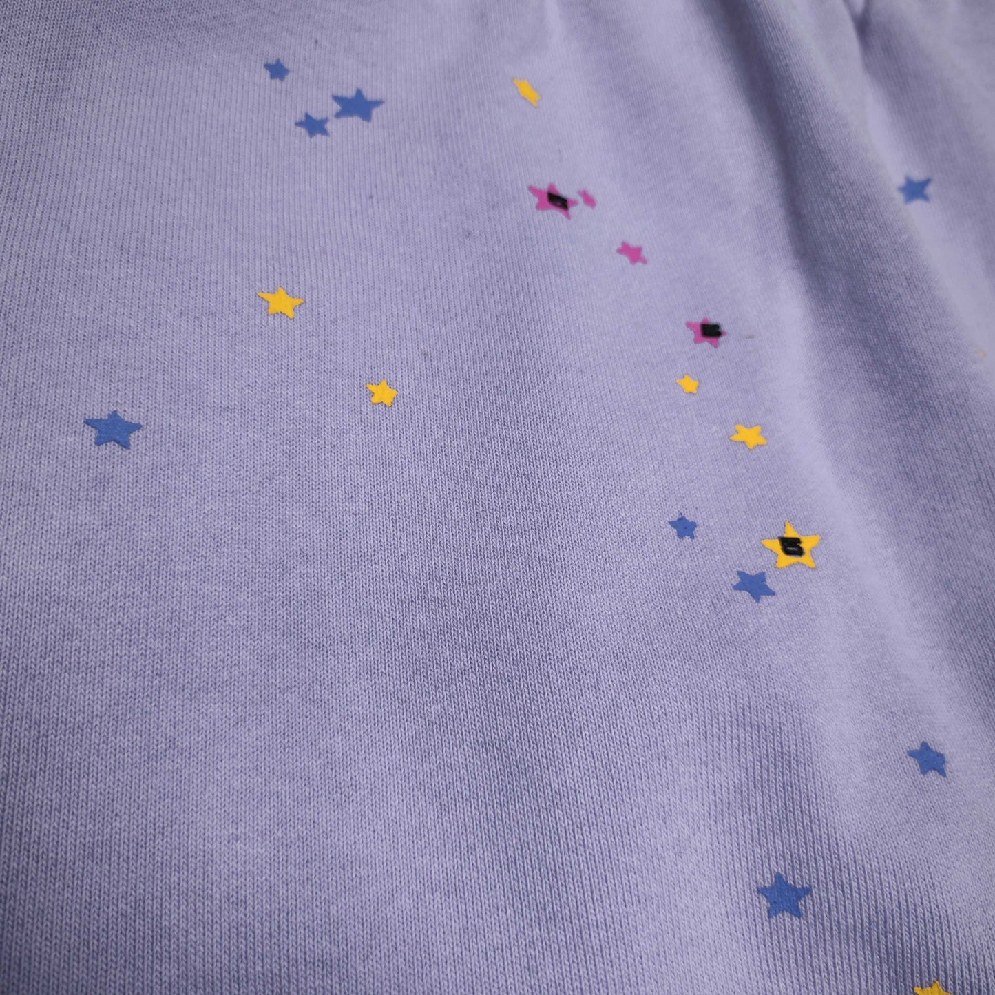 Scattered multicolor star graphics on SP5DER Acai purple sweatpants