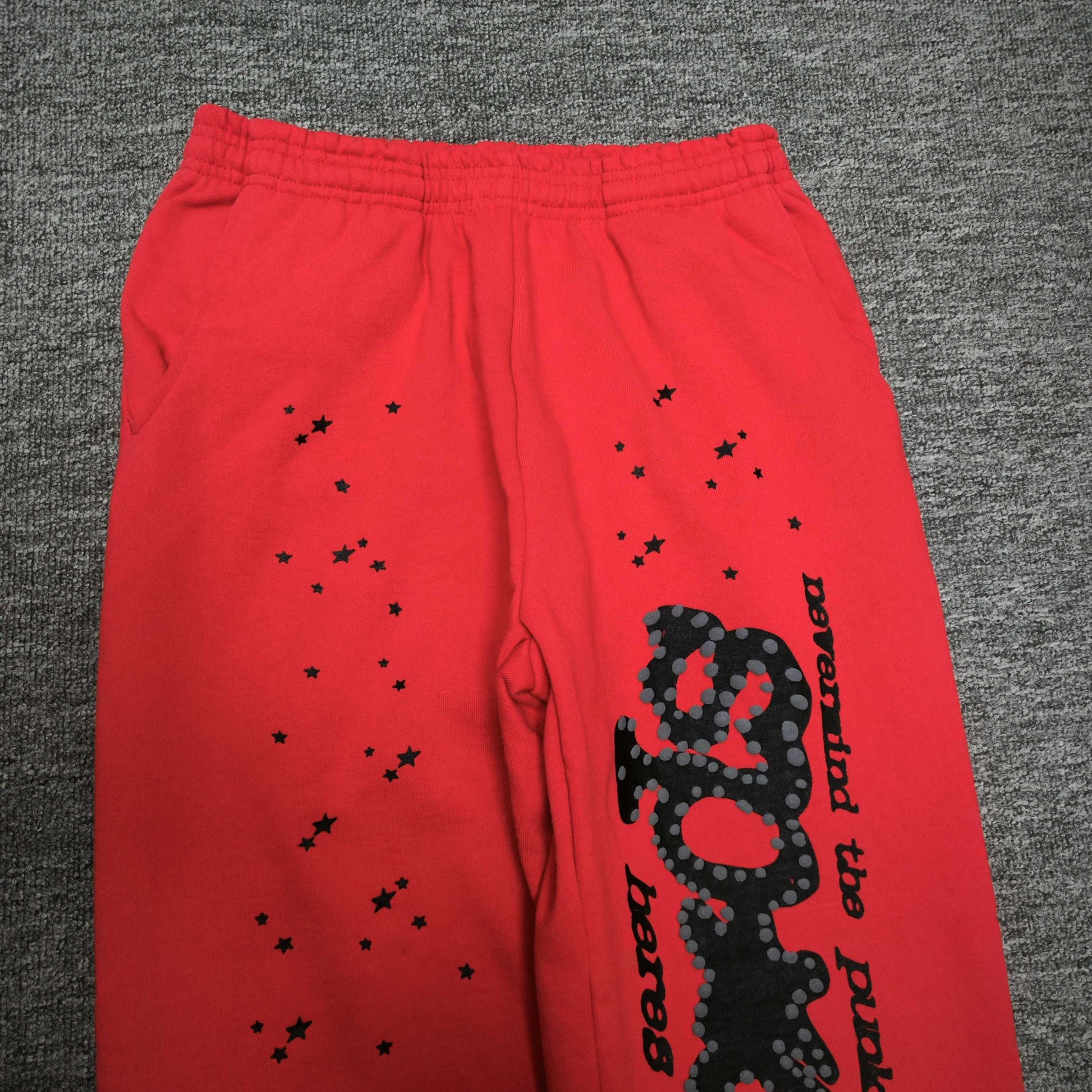 Black SP5DER leg graphic slogan and star prints on red P*NK V2 sweatpants