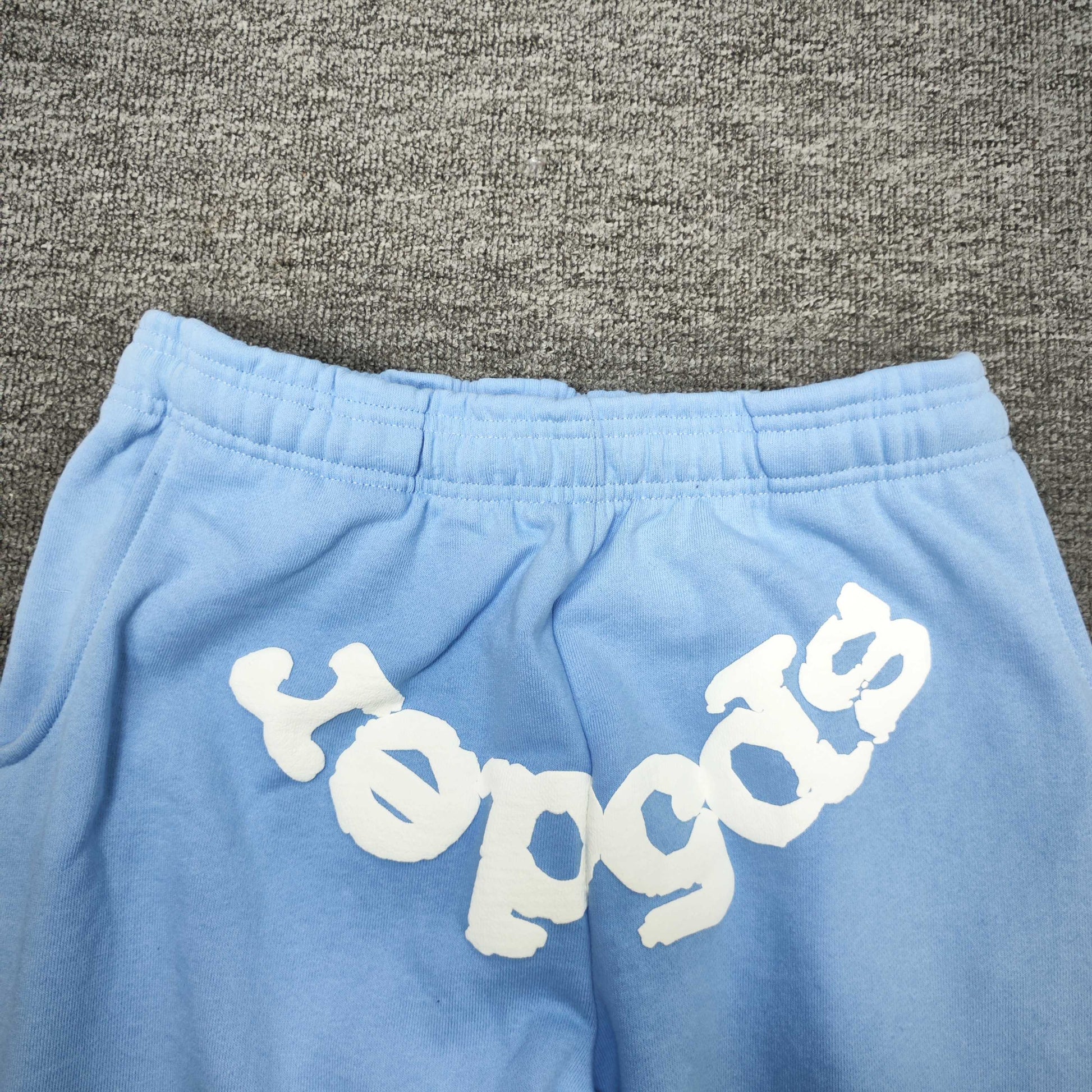White inverted SP5DER logo on Classic sky blue sweatpants
Close-up of white SP5DER puff-print logo on sky blue Classic sweatpants