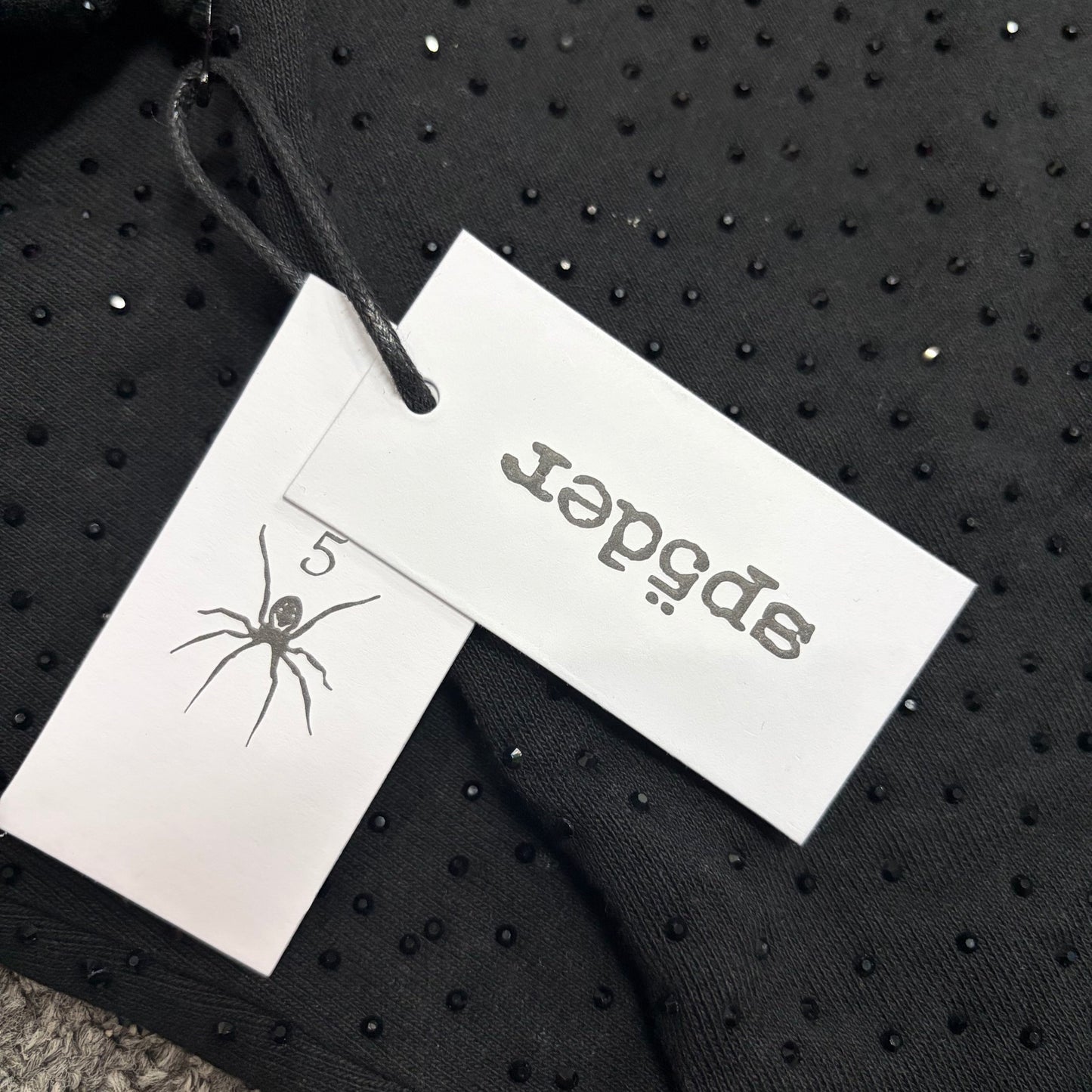 Sp5der VVS Hoodie neck label and size tag detail
Sp5der VVS Hoodie care label and washing instruction detail