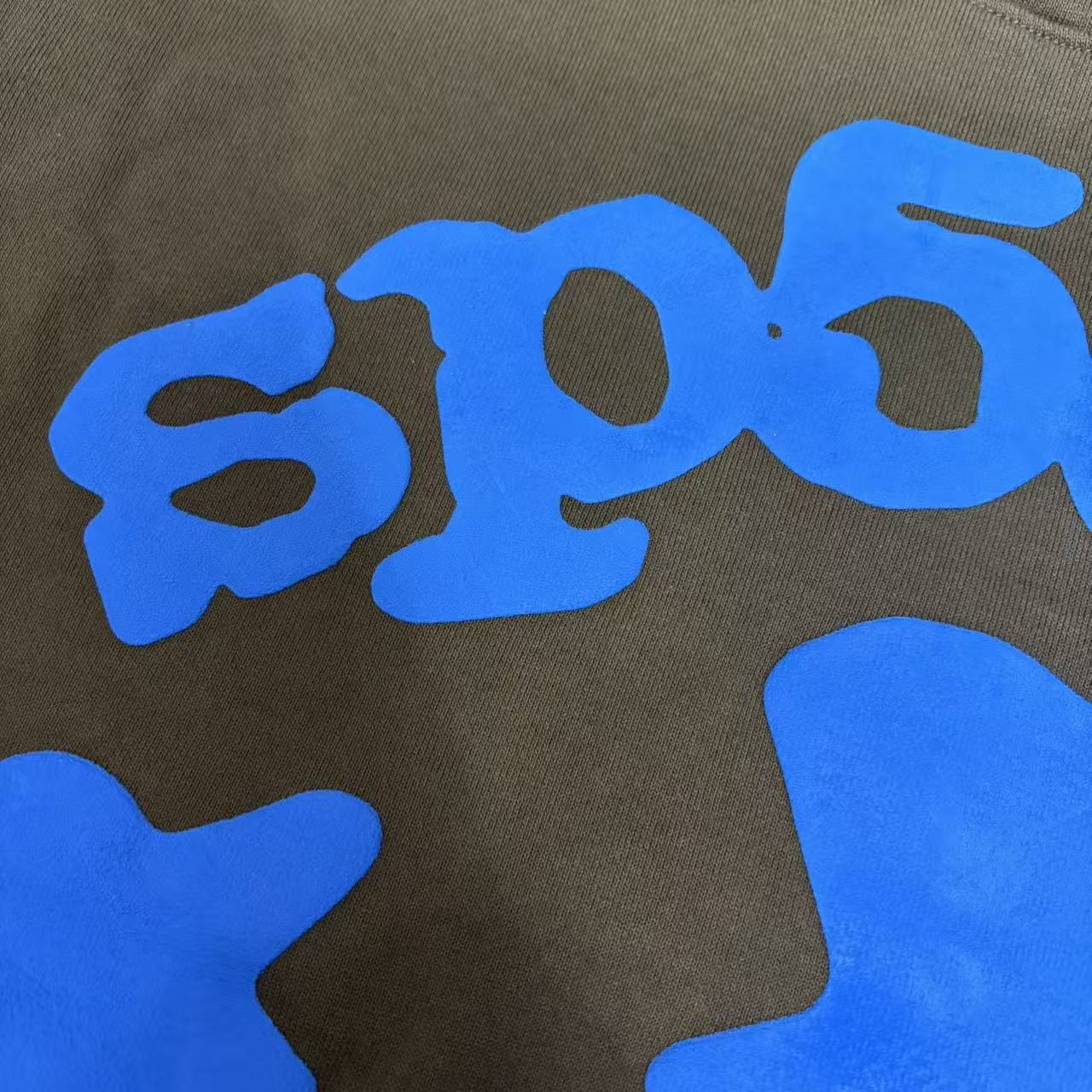 Full blue puff-print artwork on Sp5der Beluga Hoodie Brown with logo, stars and number graphics
Close-up of raised blue SP5DER lettering and clean puff-print edges on the brown Beluga Hoodie
Side angle showing the three-dimensional blue puff-print texture on Sp5der Beluga Hoodie Brown
Oversized blue star graphics across the front of Sp5der Beluga Hoodie Brown