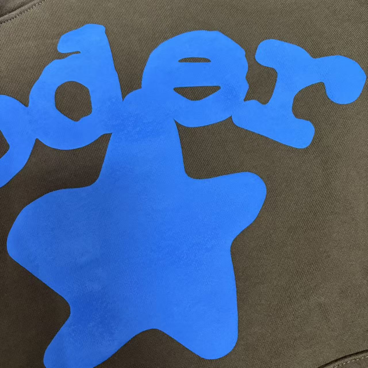 Full blue puff-print artwork on Sp5der Beluga Hoodie Brown with logo, stars and number graphics
Close-up of raised blue SP5DER lettering and clean puff-print edges on the brown Beluga Hoodie
Side angle showing the three-dimensional blue puff-print texture on Sp5der Beluga Hoodie Brown
Oversized blue star graphics across the front of Sp5der Beluga Hoodie Brown