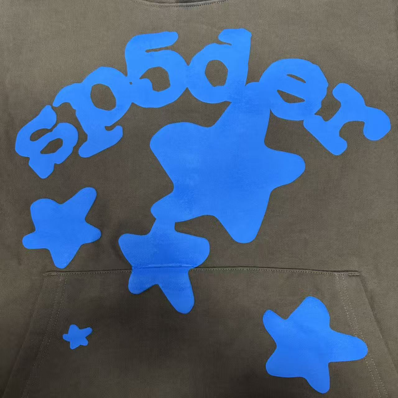 Full blue puff-print artwork on Sp5der Beluga Hoodie Brown with logo, stars and number graphics
Close-up of raised blue SP5DER lettering and clean puff-print edges on the brown Beluga Hoodie
Side angle showing the three-dimensional blue puff-print texture on Sp5der Beluga Hoodie Brown
Oversized blue star graphics across the front of Sp5der Beluga Hoodie Brown