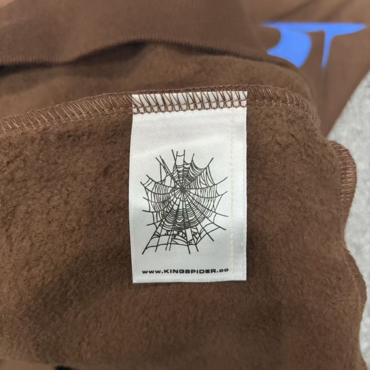 Sp5der Beluga Hoodie Brown neck label and size tag detail
Sp5der Beluga Hoodie Brown care label and washing instruction detail