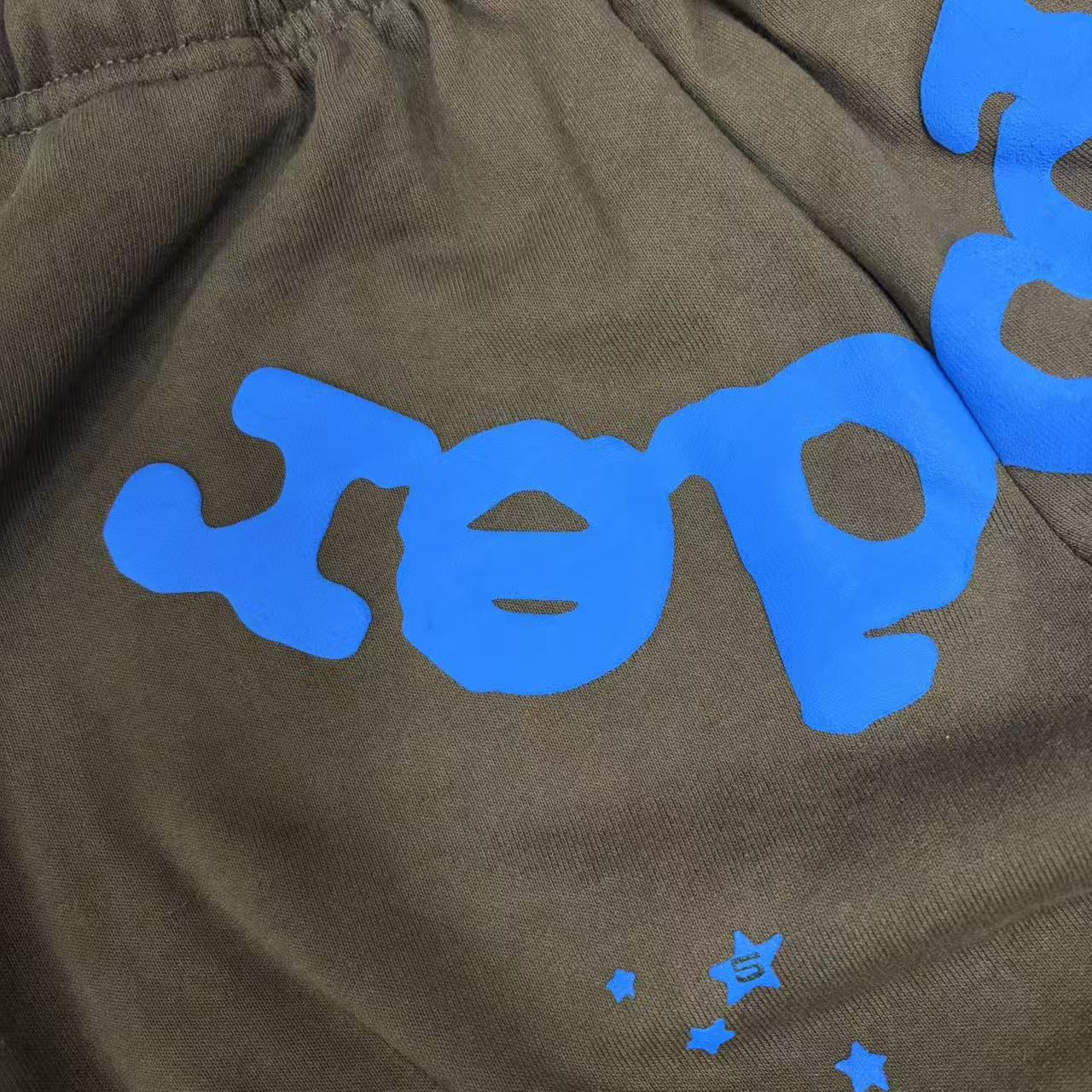 Close-up of blue SP5DER puff-print logo on Beluga V2 brown sweatpants