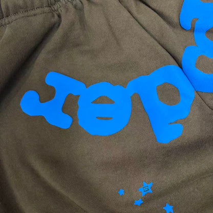 Close-up of blue SP5DER puff-print logo on Beluga V2 brown sweatpants