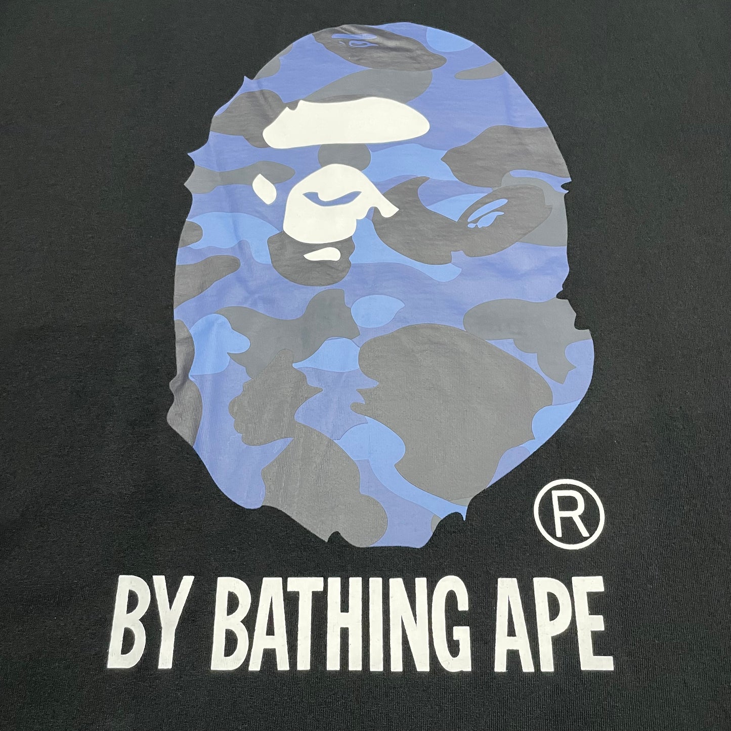 Close-up of blue ABC Camo Ape Head rubber print on black T-shirt