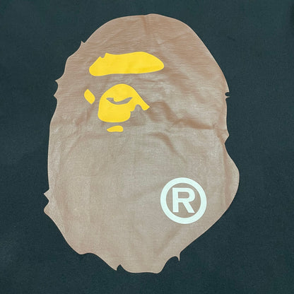 Close-up of brown and yellow Ape Head graphic on black BAPE T-shirt