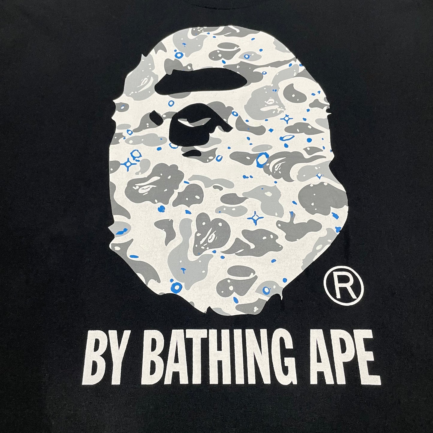 Close-up of grey white and blue Space Camo Ape Head graphic on black BAPE T-shirt