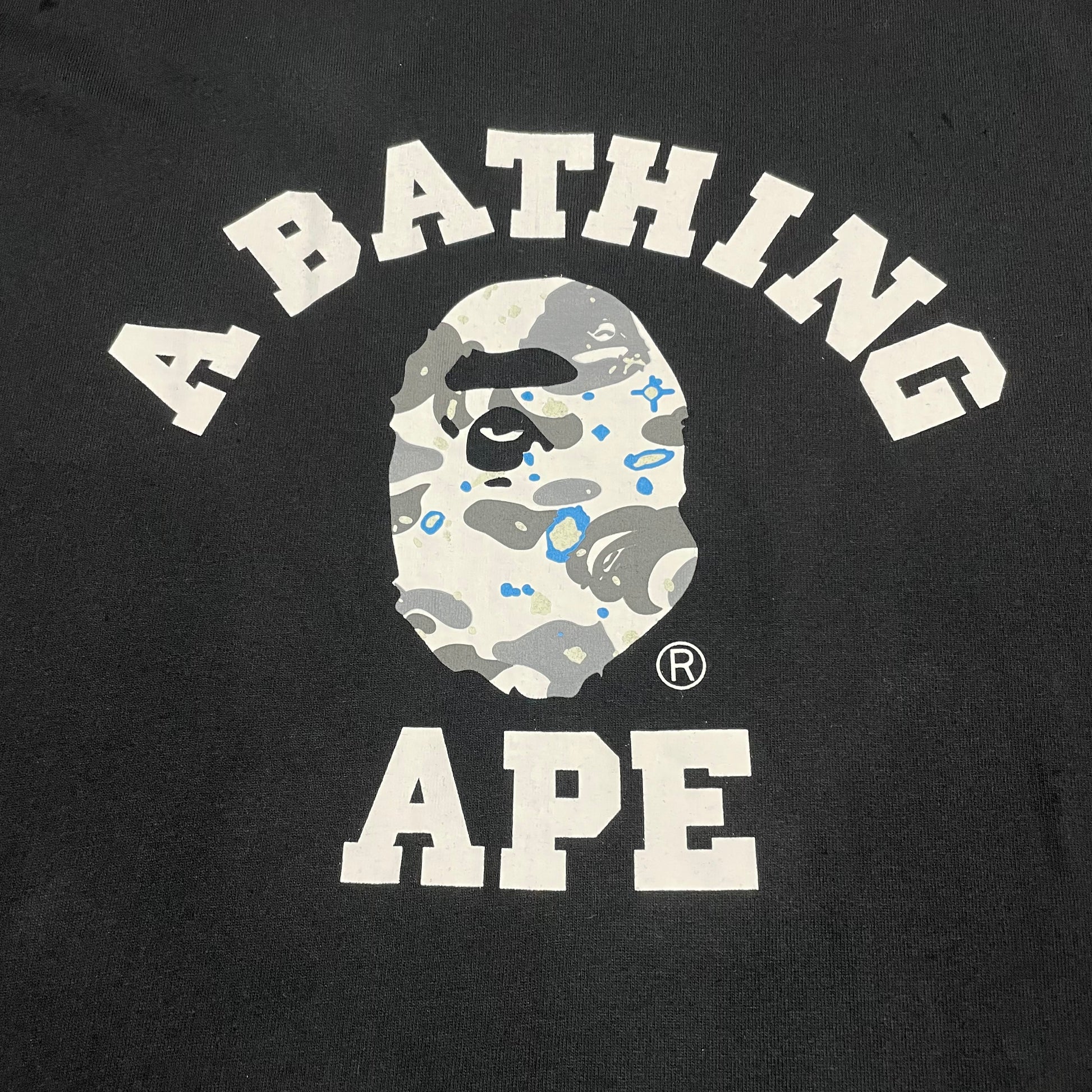 White and grey Space Camo College graphic on black BAPE T-shirt
Close-up of white Space Camo Ape Head graphic on black BAPE T-shirt
Detailed grey white and blue Space Camo pattern on black BAPE T-shirt
