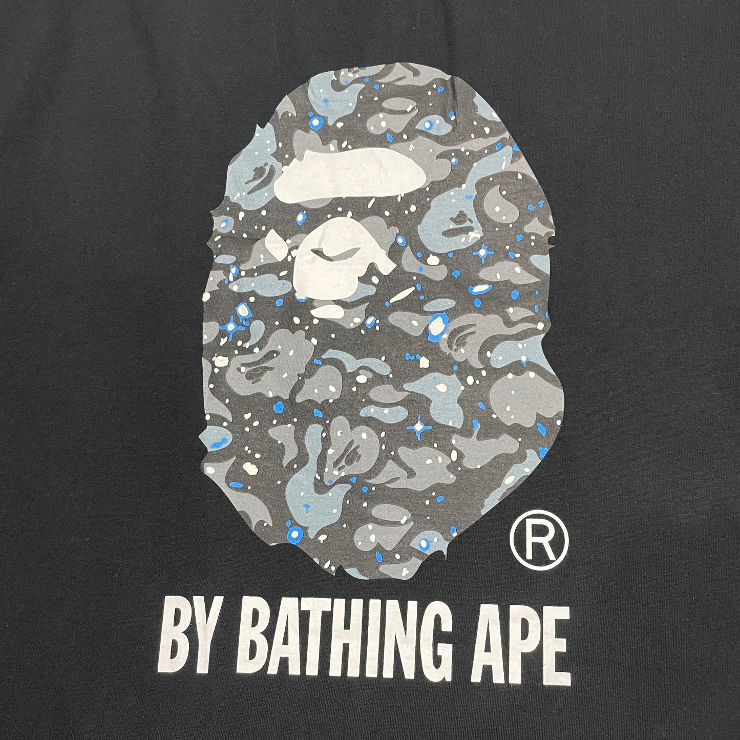 Large grey Space Camo Ape Head graphic on black BAPE T-shirt
Close-up of Space Camo Ape Head print on black BAPE T-shirt
Detailed grey white and blue Space Camo pattern on black BAPE T-shirt
White By Bathing Ape lettering detail on black Space Camo T-shirt