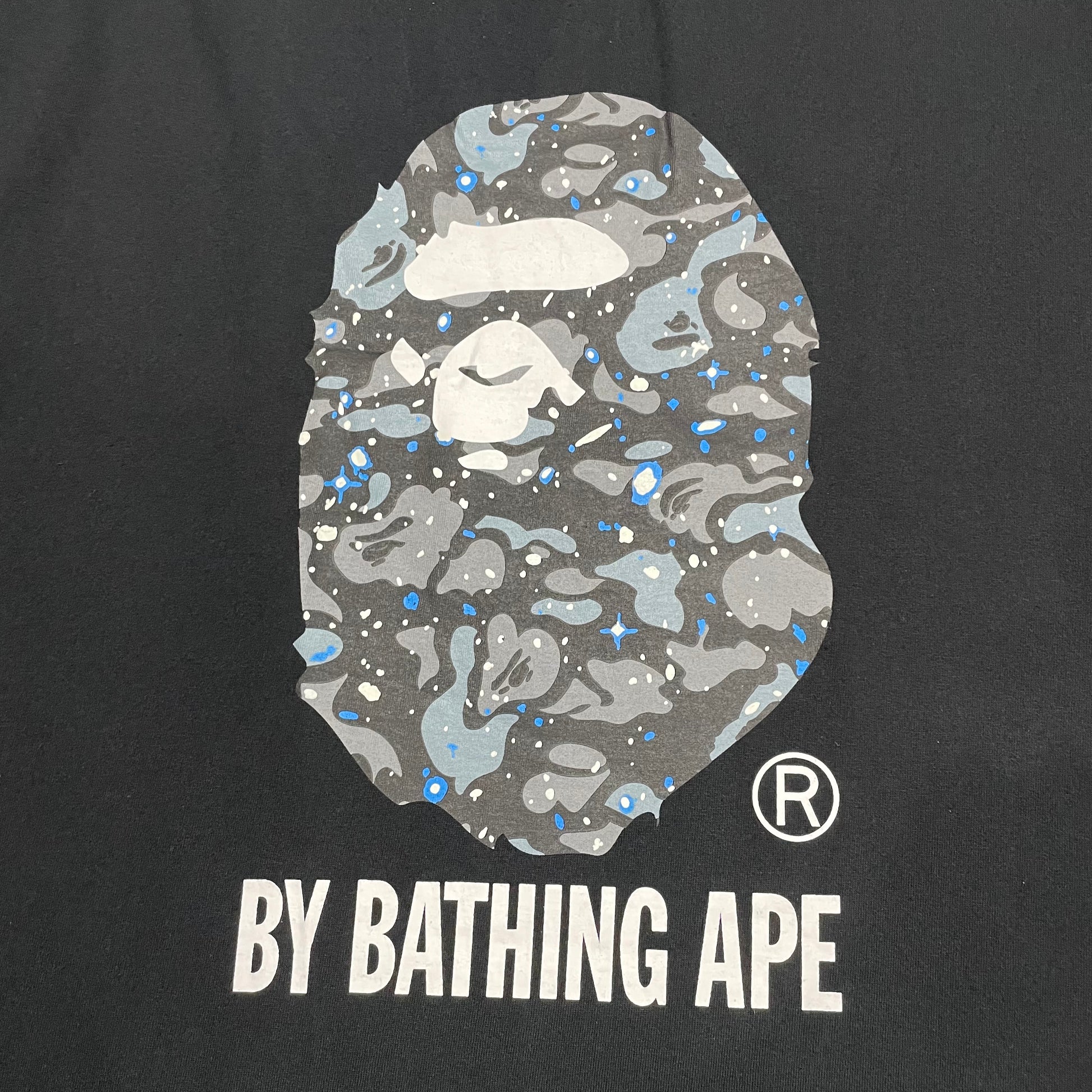 Large grey Space Camo Ape Head graphic on black BAPE T-shirt
Close-up of Space Camo Ape Head print on black BAPE T-shirt
Detailed grey white and blue Space Camo pattern on black BAPE T-shirt
White By Bathing Ape lettering detail on black Space Camo T-shirt