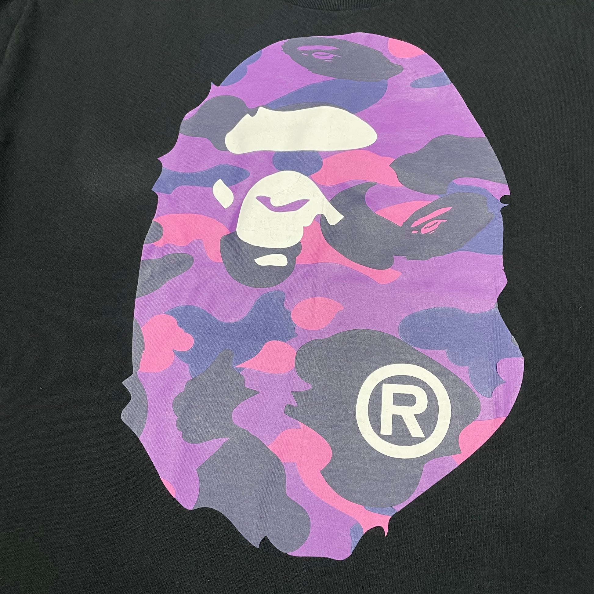 Large purple Color Camo Ape Head front graphic on black BAPE T-shirt
Close-up of purple Color Camo Big Ape Head rubber print on black BAPE T-shirt
Detailed purple pink and navy Color Camo pattern on black BAPE T-shirt
