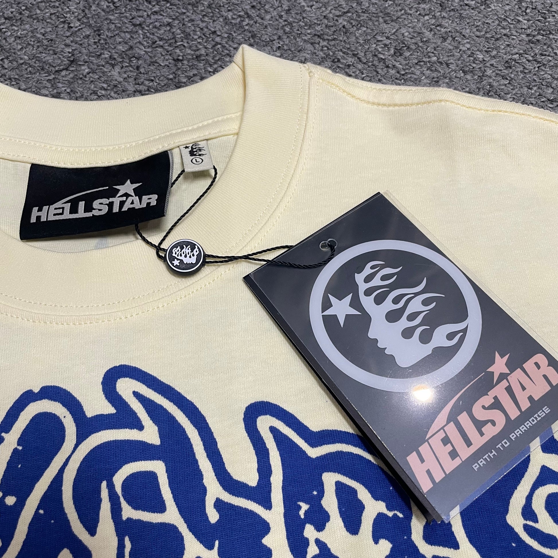 Hellstar Yoga T-shirt wash label showing size, fabric composition and garment care information
Hellstar branded hangtag attached to the Yoga School of Enlightenment cream graphic T-shirt