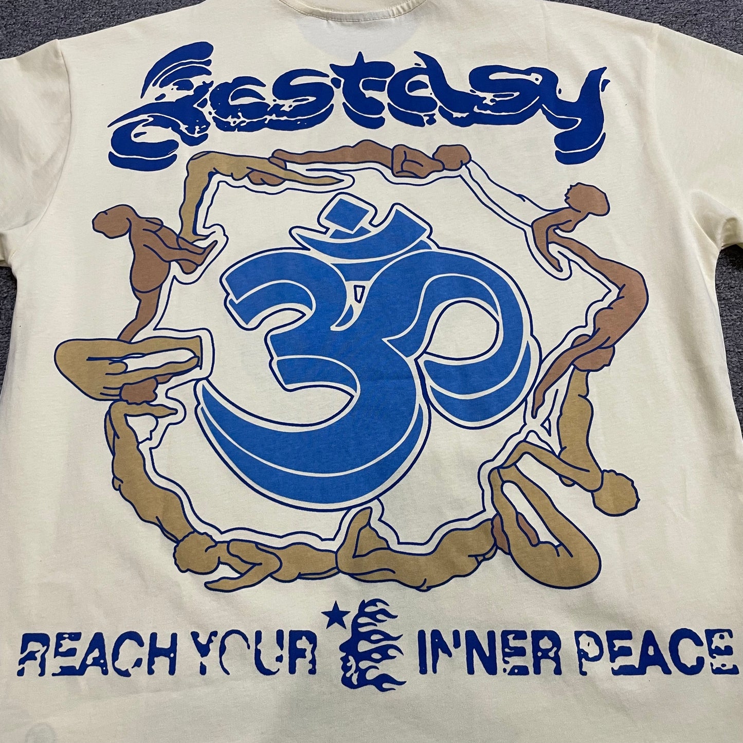 Full front graphic of the Hellstar Yoga School of Enlightenment T-Shirt with blue meditation figure artwork
Full back graphic of the Hellstar Yoga T-Shirt featuring a large blue Om symbol and Reach Your Inner Peace artwork
Close-up of the blue and tan yoga figure print on the Hellstar School of Enlightenment T-Shirt
Detailed view of the distressed lettering and layered blue and tan print on the Hellstar Yoga graphic T-shirt