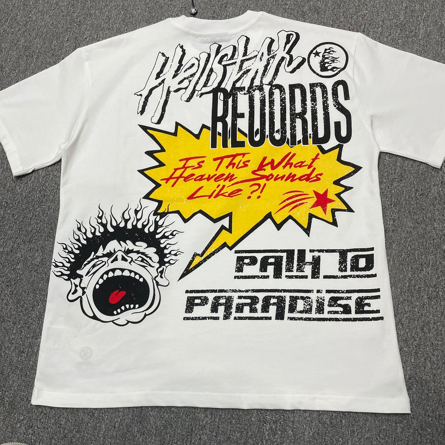 Full Hellstar Records Hollywood graphic print on the Path to Paradise T-Shirt
Close-up of the distressed Hellstar Records and Hollywood lettering print
Detailed view of the distressed red black and white print texture on the Hellstar T-Shirt
Oversized screaming-face side graphic with flame details on the Hellstar Path to Paradise T-Shirt
Close-up of the flame and open-mouth side artwork on the Hellstar graphic T-shirt
Full back graphic artwork on the Hellstar Path to Paradise Records T-Shirt
