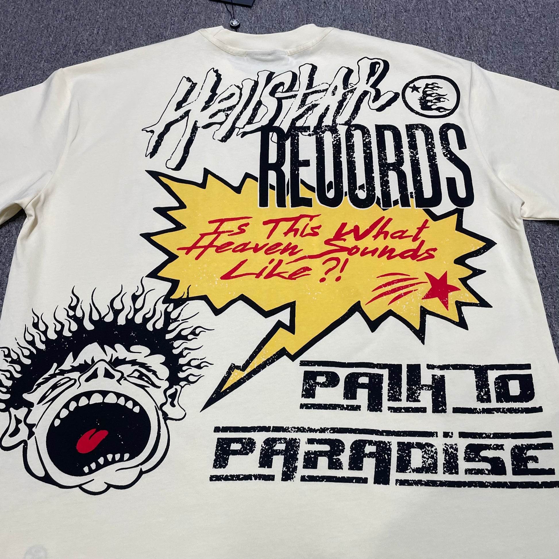 Full Hellstar Records Hollywood graphic print on the Path to Paradise T-Shirt
Close-up of the distressed Hellstar Records and Hollywood lettering print
Detailed view of the distressed red black and white print texture on the Hellstar T-Shirt
Oversized screaming-face side graphic with flame details on the Hellstar Path to Paradise T-Shirt
Close-up of the flame and open-mouth side artwork on the Hellstar graphic T-shirt
Full back graphic artwork on the Hellstar Path to Paradise Records T-Shirt