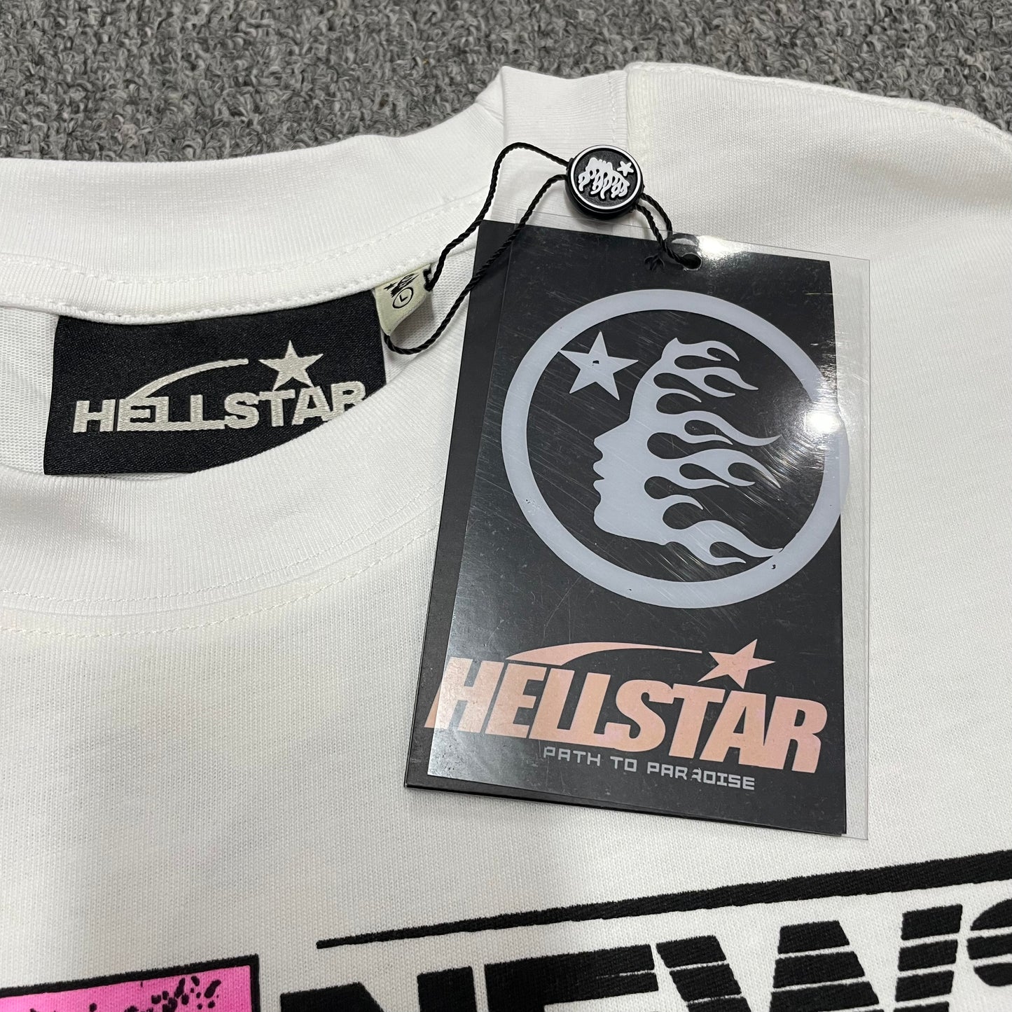 Hellstar branded neck label and crew-neck stitching on the Breaking News T-Shirt
Hellstar Breaking News T-Shirt wash label showing fabric size and garment care information
Size label detail inside the Hellstar Breaking News graphic T-shirt
Hellstar branded hangtag attached to the white Breaking News graphic T-shirt