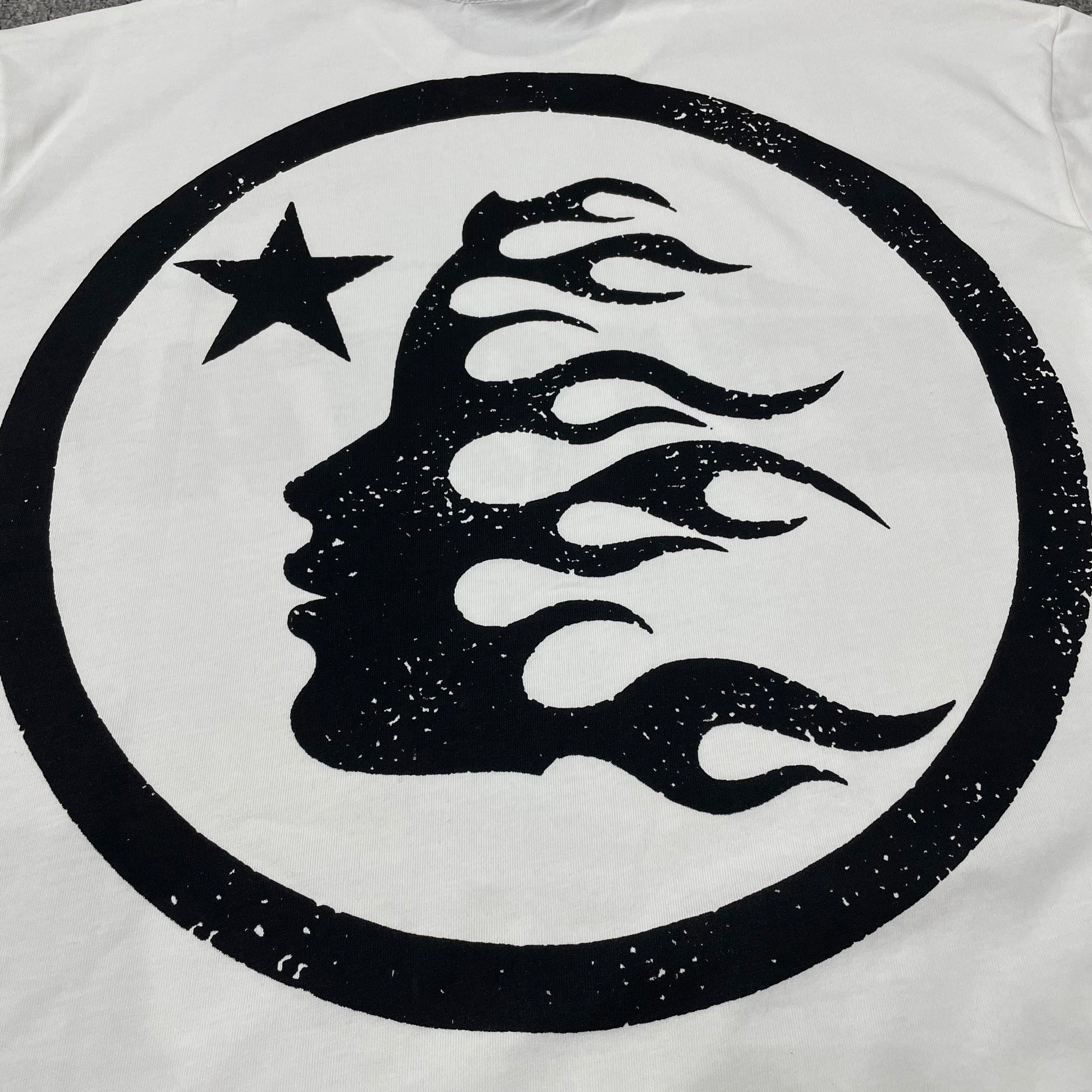 Full oversized Hellstar Sports wordmark graphic printed across the front of the white T-shirt
Close-up of the black Hellstar wordmark and shooting-star graphic on the white Sports Logo T-Shirt
Detailed view of the black graphic print texture on the Hellstar Sports Logo white T-shirt
Close-up of the shooting-star graphic above the Hellstar logo on the white T-shirt
