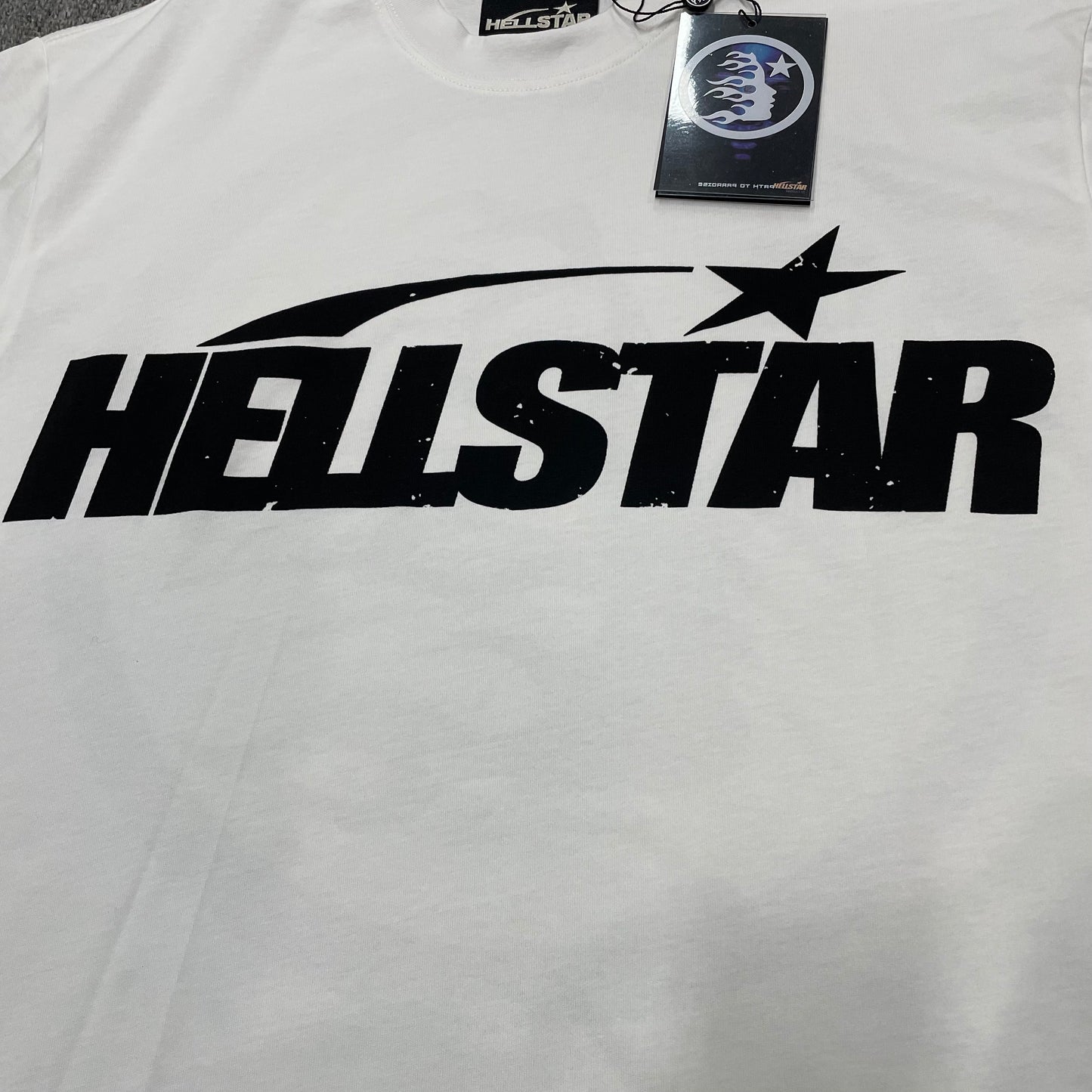 Full oversized Hellstar Sports wordmark graphic printed across the front of the white T-shirt
Close-up of the black Hellstar wordmark and shooting-star graphic on the white Sports Logo T-Shirt
Detailed view of the black graphic print texture on the Hellstar Sports Logo white T-shirt
Close-up of the shooting-star graphic above the Hellstar logo on the white T-shirt