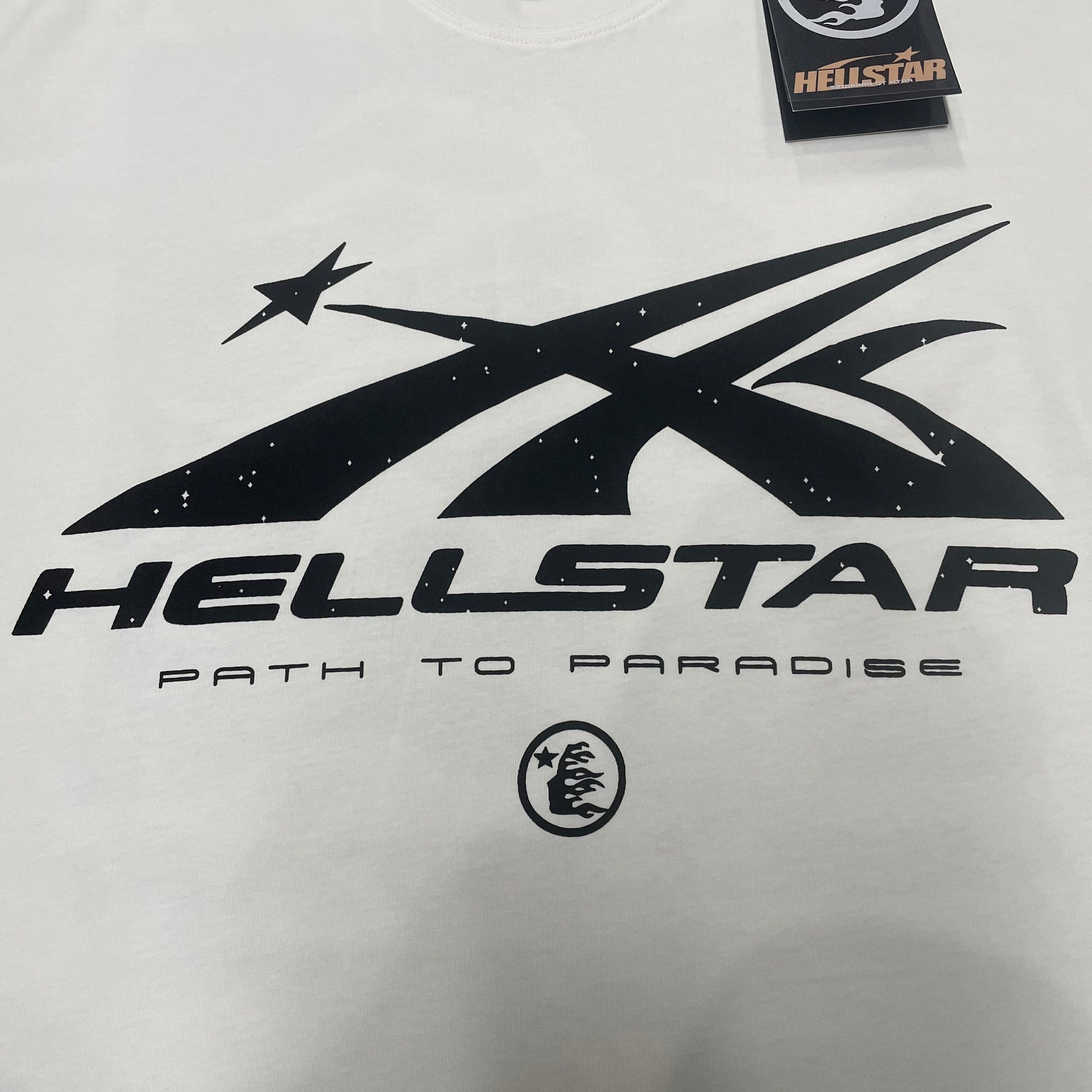 Full black Hellstar Path to Paradise logo graphic printed across the front of the white T-shirt
