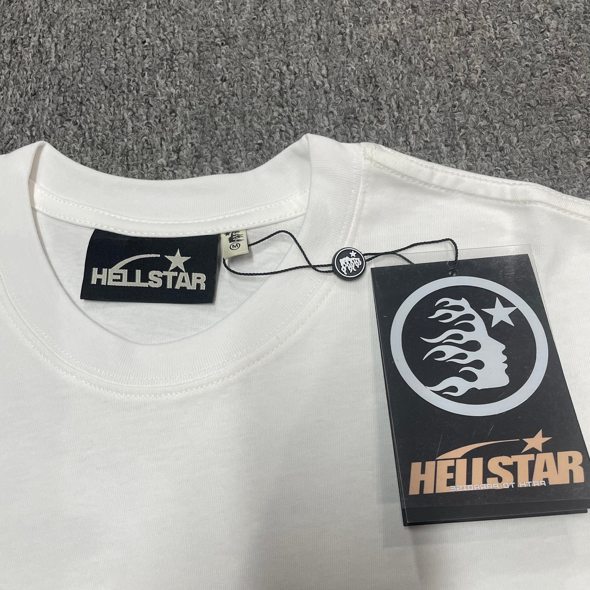 Hellstar branded neck label and crew-neck stitching on the Path to Paradise T-Shirt
White ribbed crew-neck and stitching detail on the Hellstar graphic T-shirt
Size label detail inside the white Hellstar Path to Paradise graphic T-shirt
Hellstar branded hangtag attached to the white Path to Paradise Logo T-Shirt
