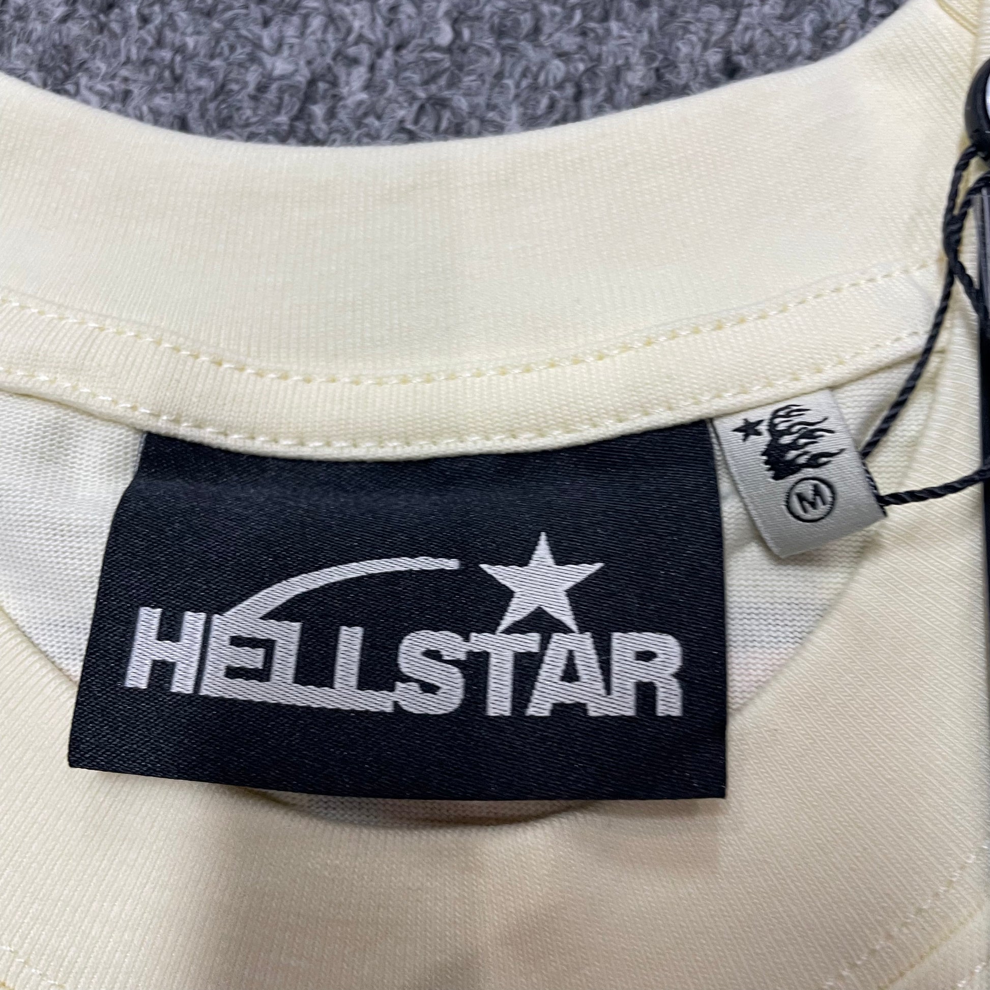 Hellstar branded neck label and crew-neck stitching on the Human Development T-Shirt
Size label detail inside the cream Hellstar Human Development T-Shirt
Cream ribbed crew-neck collar and stitching detail on the Hellstar graphic T-shirt