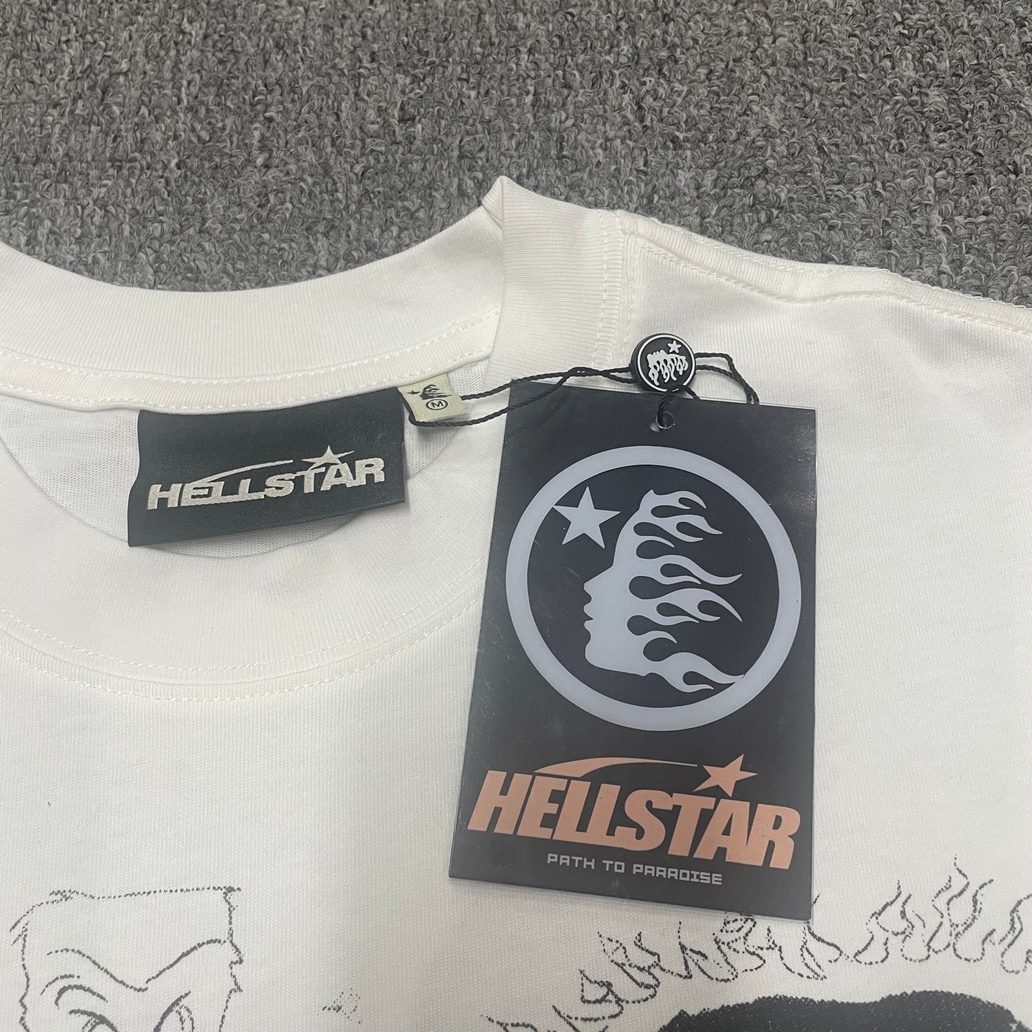 White ribbed crew-neck collar and stitching detail on the Hellstar graphic T-shirt
Size label detail inside the white Hellstar Sports Family graphic T-shirt
Hellstar branded neck label and crew-neck stitching on the Sports Family T-Shirt