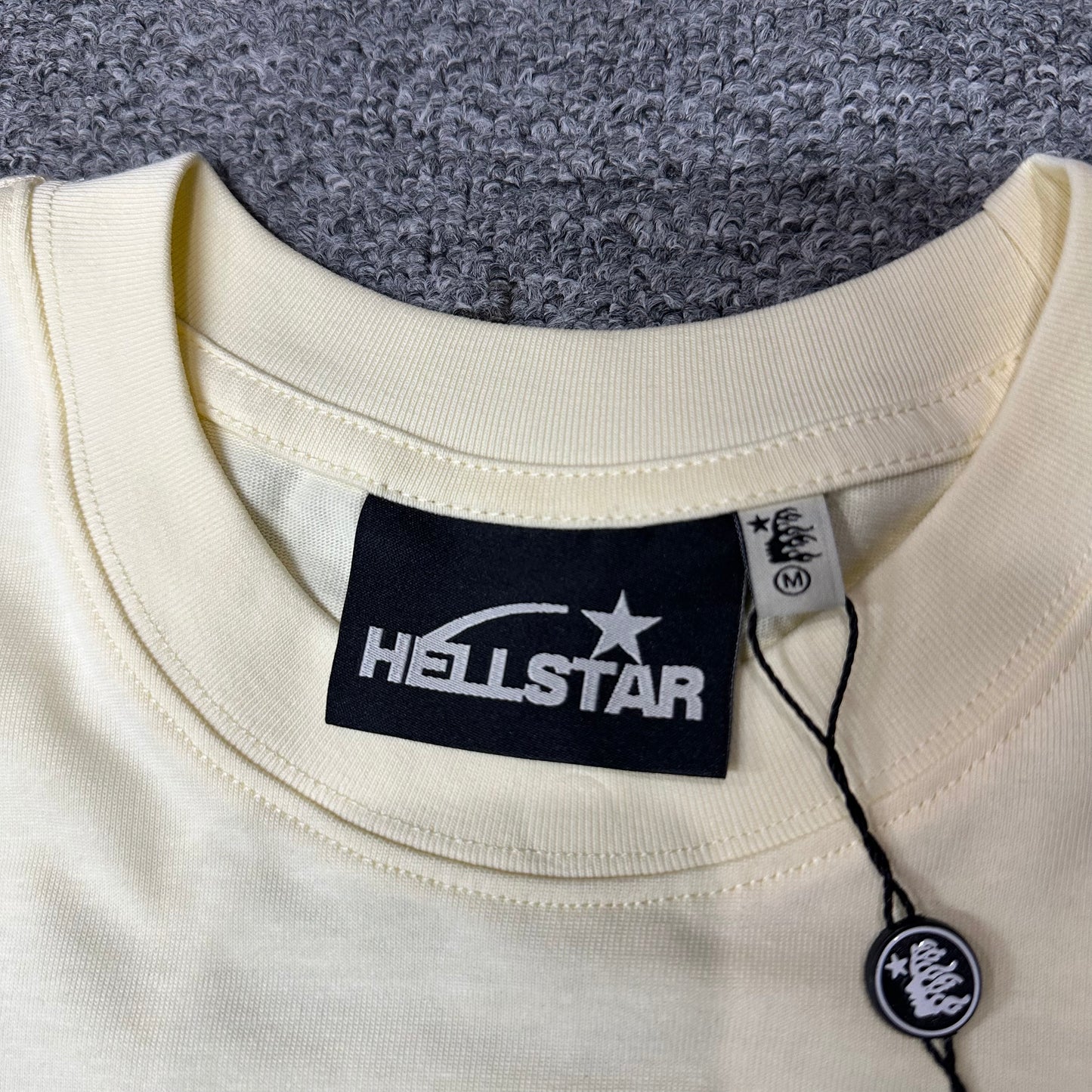Hellstar branded neck label and crew-neck stitching on the Classic Logo T-Shirt
Cream ribbed crew-neck collar and stitching detail on the Hellstar graphic T-shirt
Size label detail inside the cream Hellstar Classic Logo T-Shirt