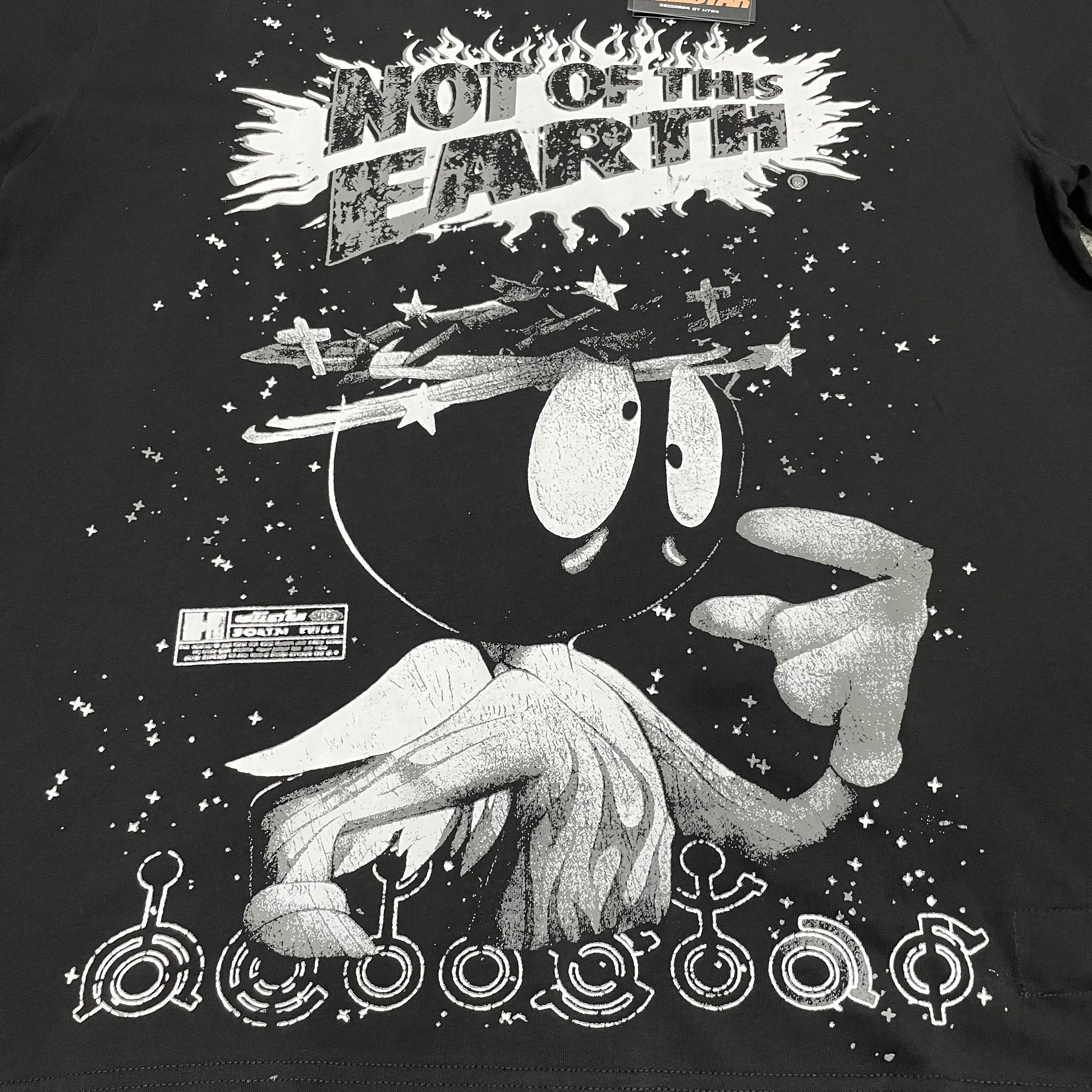 Full Not of This Earth graphic printed across the front of the black Hellstar T-Shirt
Not of This Earth slogan printed above the cartoon-style space character graphic
Flame-shaped lettering detail around the Not of This Earth slogan
Oversized cartoon-style space character graphic on the Hellstar Not of This Earth T-Shirt