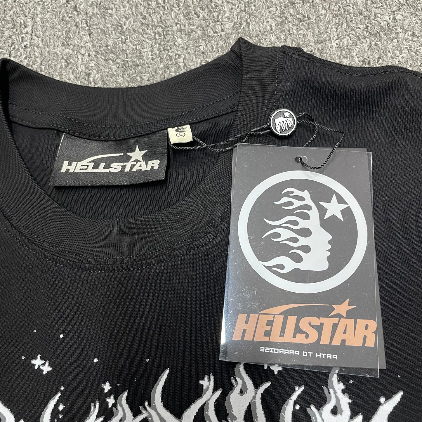 Hellstar branded neck label and crew-neck stitching on the Not of This Earth T-Shirt
Black ribbed crew-neck collar and stitching detail on the Hellstar graphic T-shirt
Size label detail inside the black Hellstar Not of This Earth graphic T-shirt