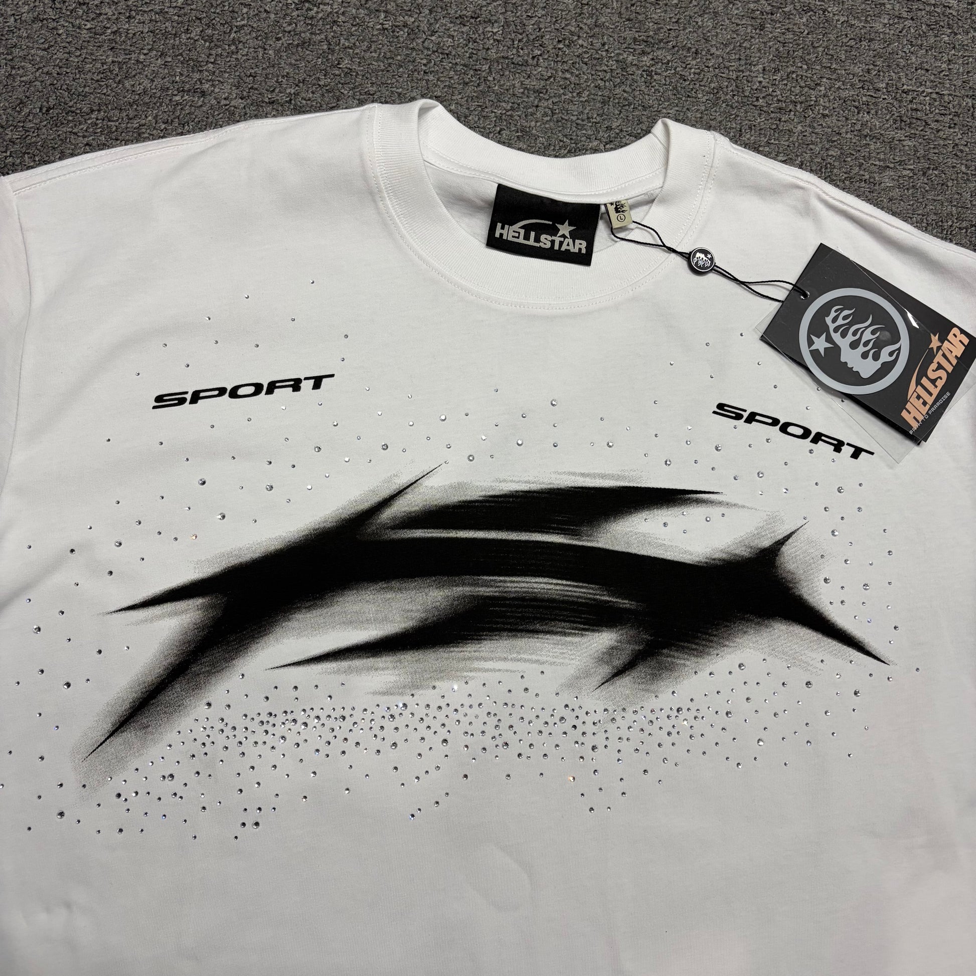 Full distorted black Blur graphic printed across the front of the white Hellstar T-Shirt
Reflective rhinestone details surrounding the front graphic on the Hellstar Blur T-Shirt
Small SPORT lettering printed above the left side of the Hellstar Blur chest graphic