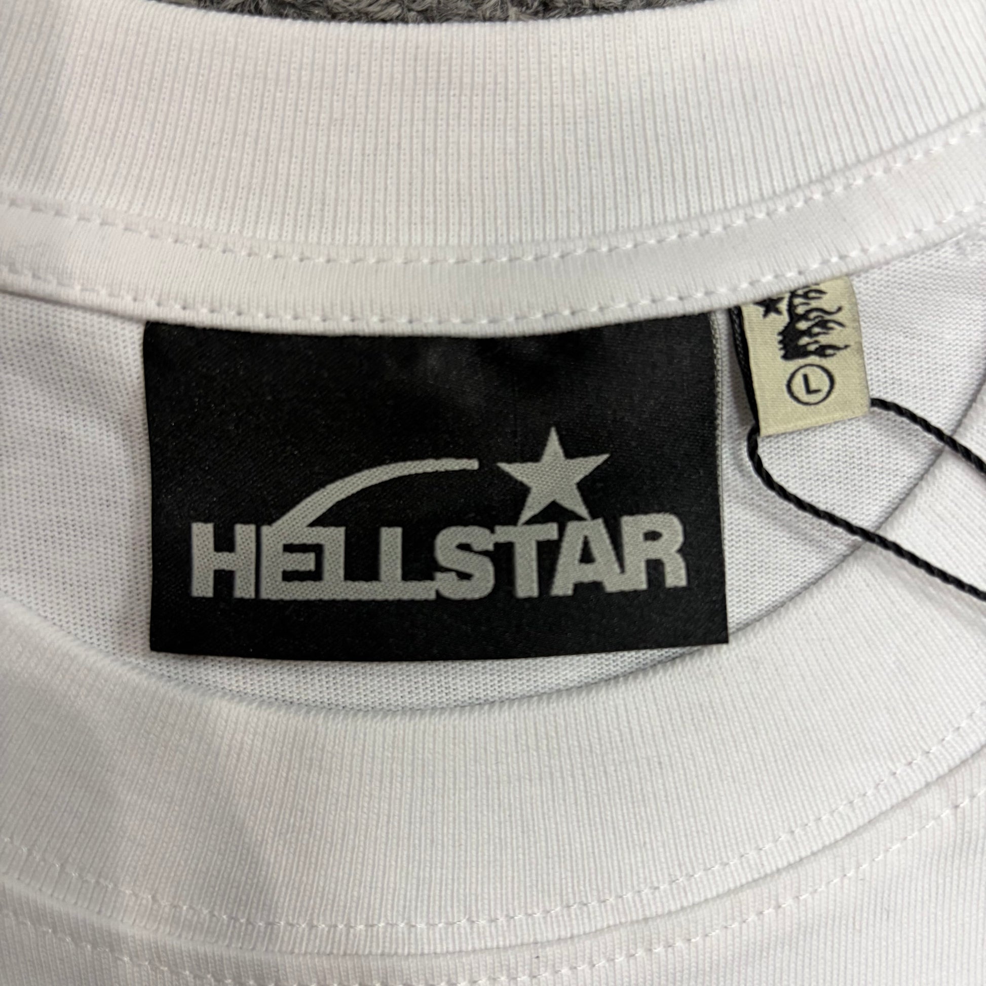 Hellstar branded neck label and crew-neck stitching on the white Blur T-Shirt
Size label detail inside the white Hellstar Blur T-Shirt
White ribbed crew-neck collar and stitching detail on the Hellstar Blur graphic T-shirt