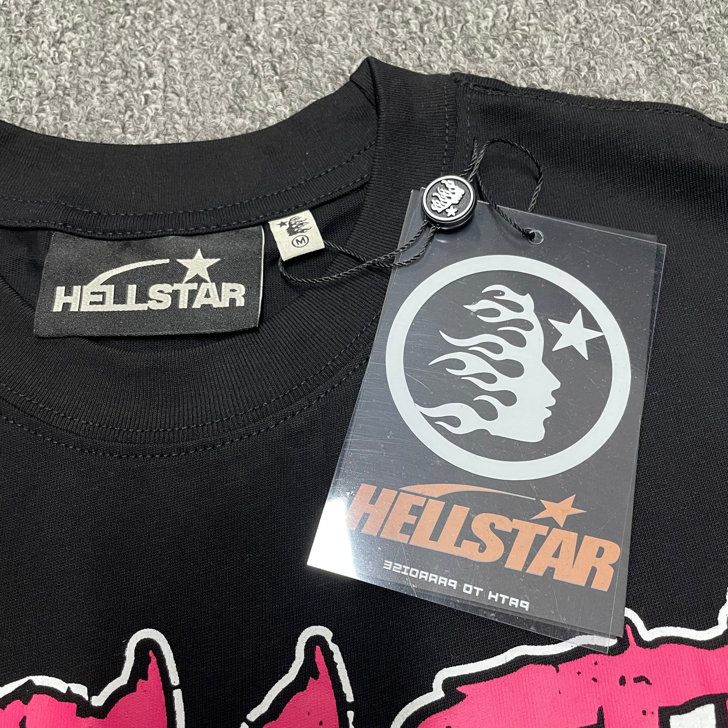 Hellstar branded neck label and crew-neck stitching on the Adventure Astronaut T-Shirt
Black ribbed crew-neck collar and stitching detail on the Hellstar graphic T-shirt
Size label detail inside the black Hellstar Adventure Astronaut T-Shirt
Front view of the Hellstar flame and star logo hangtag
