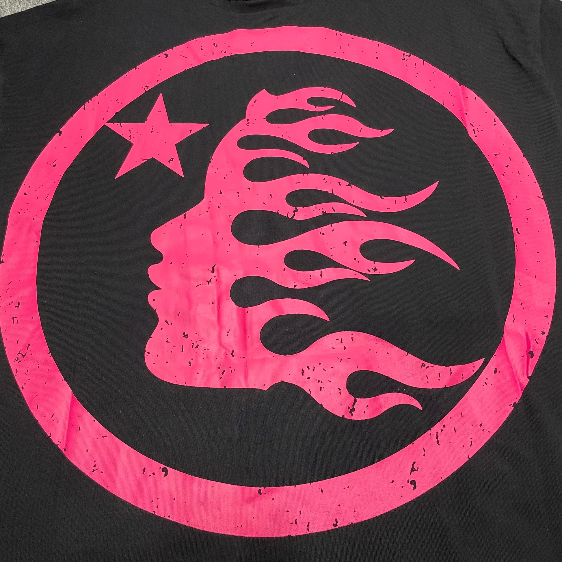Full oversized pink circular graphic printed on the back of the Hellstar Adventure T-Shirt
Pink flame-profile character inside the circular back graphic on the Hellstar T-Shirt
White star detail inside the oversized pink Hellstar back graphic