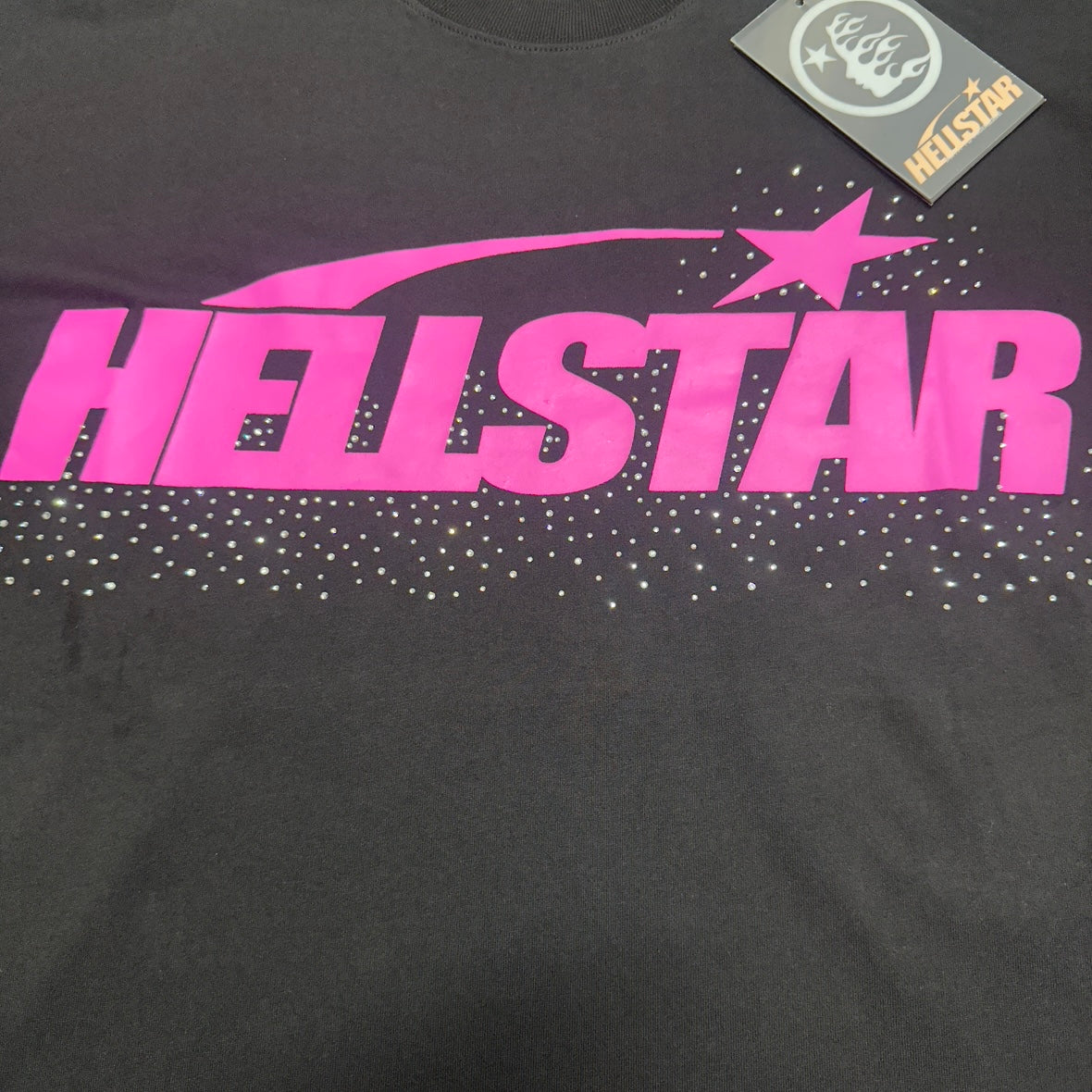 Hellstar Classic Rhinestone Logo T-Shirt black front view with pink logo graphic and rhinestone detail
Close-up of the pink Hellstar logo print on the black Classic Rhinestone Logo T-Shirt
Close-up of the rhinestone detail across the chest on the Hellstar Classic Rhinestone Logo T-Shirt