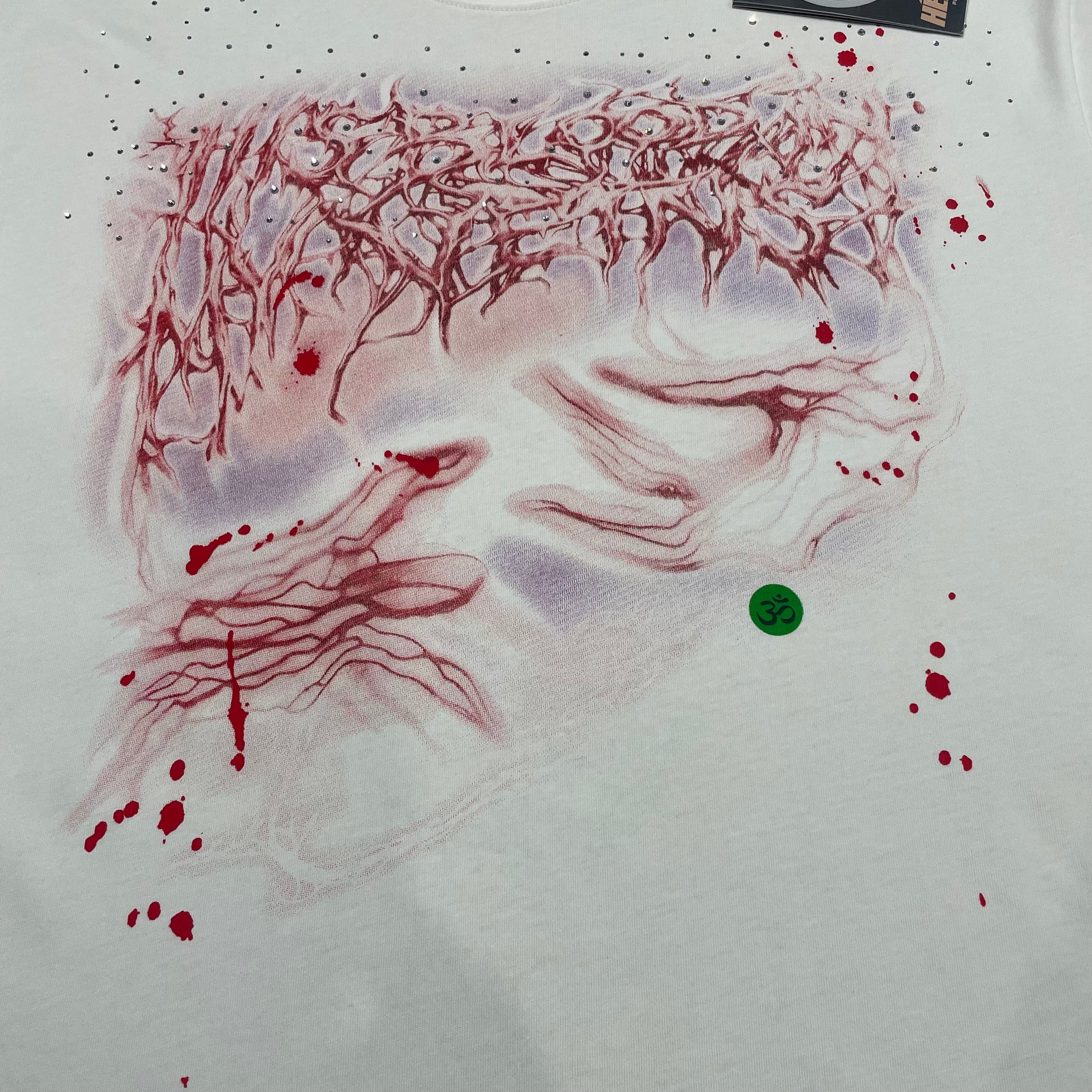 Full red and pink layered face graphic on Hellstar Red Face white T-shirt
Close-up of red face artwork and rhinestone embellishments on Hellstar white T-shirt
Close-up of crystal rhinestone details on Hellstar Red Face graphic T-shirt
Red paint splatter print detail on Hellstar Red Face white graphic T-shirt
Green Om symbol detail on Hellstar Red Face rhinestone graphic T-shirt
