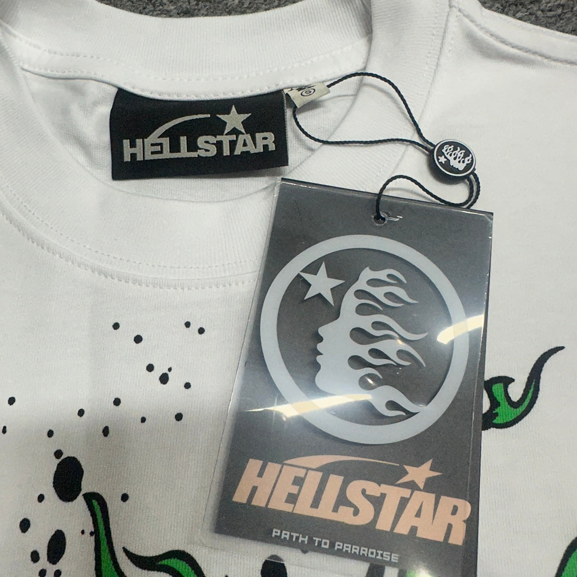 Crew neck collar and stitching detail on Hellstar Online white graphic T-shirt
Hellstar woven neck label inside the Online white graphic T-shirt
Hellstar size label detail inside the Online white graphic T-shirt
Close-up of the Hellstar branded hangtag on the Online graphic T-shirt