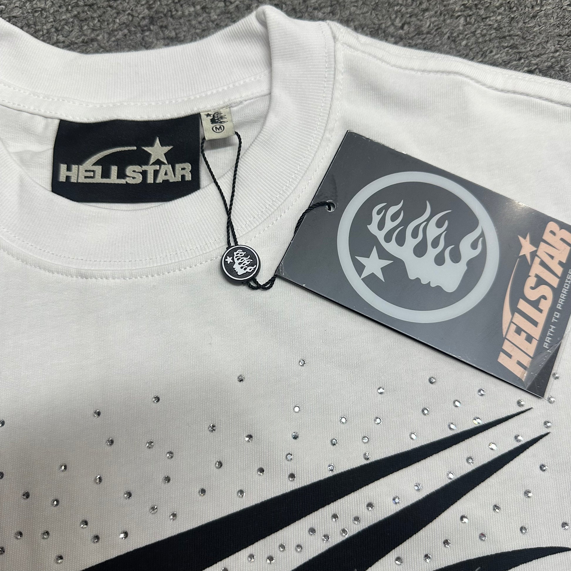Crew neck collar and stitching on Hellstar white rhinestone T-shirt
Hellstar woven neck label inside Classic Rhinestone white T-shirt
Hellstar size label detail inside white rhinestone graphic T-shirt
Hellstar branded hangtag attached to Classic Rhinestone white T-shirt